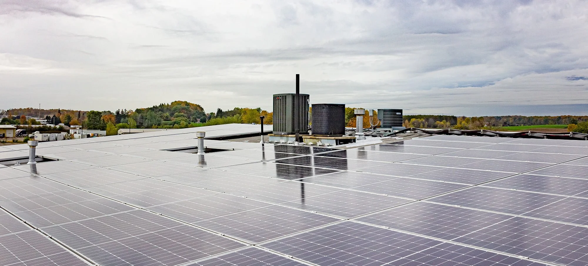 VCT Group Rooftop solar panels with HVAC units and vents, under a cloudy sky.