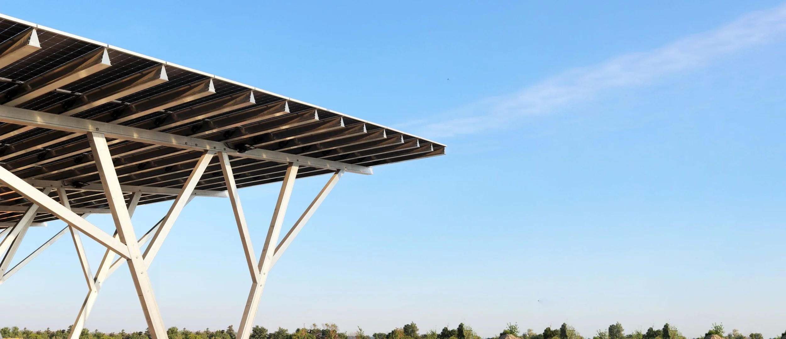 VCT Group rooftop solar panel system in Ontario, Canada. Solar panels mounted on elevated white metal supports against a blue sky with trees in the distance.