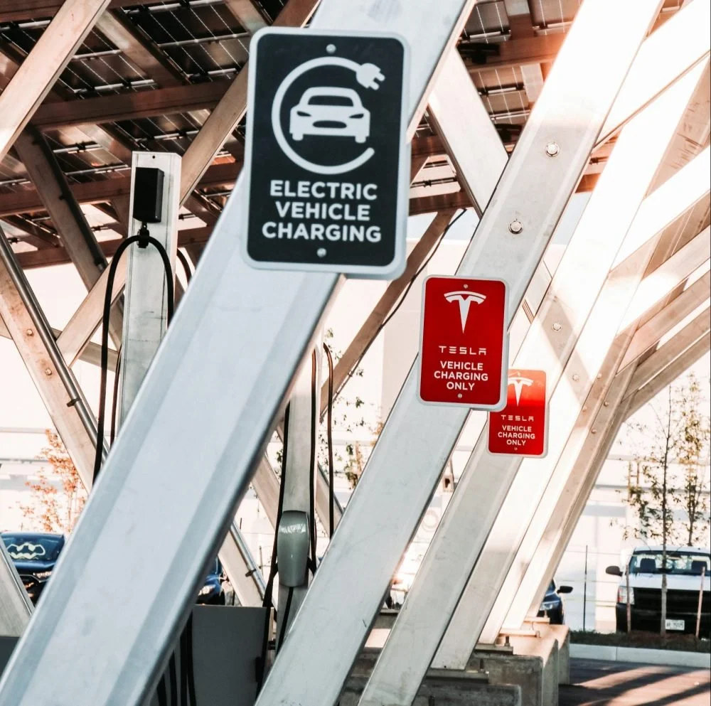 Electric vehicle charging station with signs for electric vehicle charging and Tesla vehicle charging only.