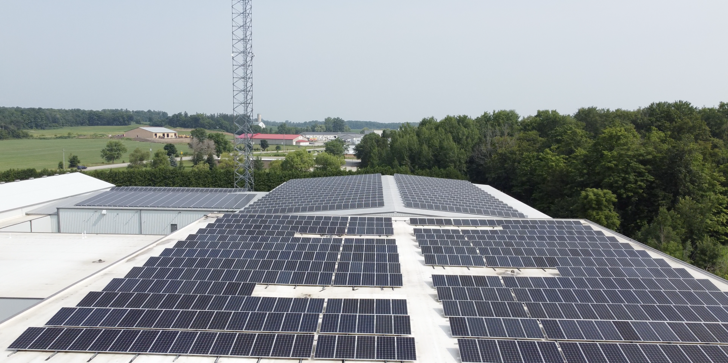 VCT Group rooftop solar panel system in Ontario, Canada. Multiple solar panels installed on the roof of a building in a rural area with trees and open fields visible in the background.