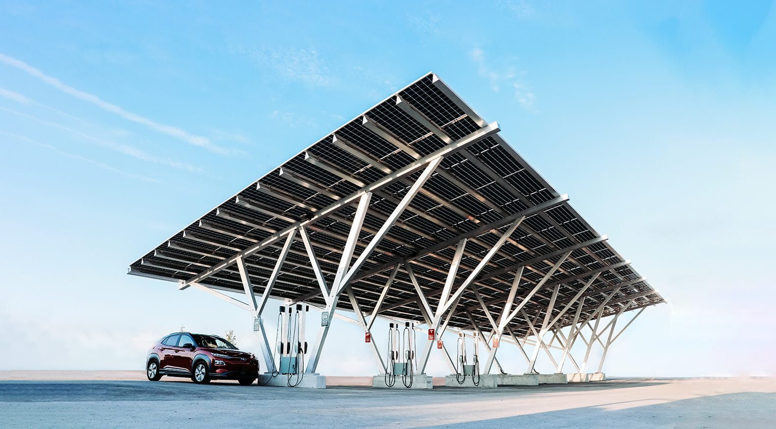 VCT Group Solar Carports & EV Charging at Pickering Casino Resort in Ontario. Electric vehicle charging station with a red car parked, solar panel canopy overhead, under a clear blue sky.