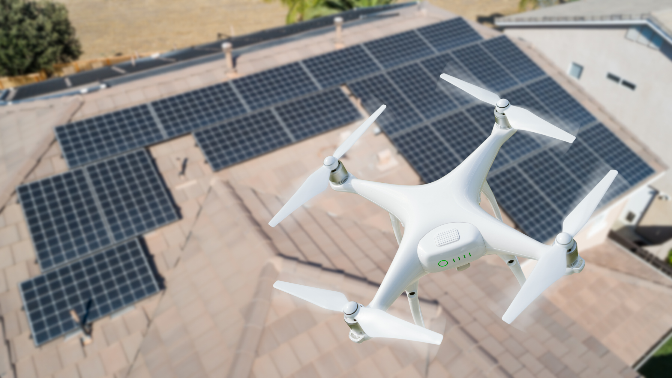 A white drone with four propellers flying over a rooftop with solar panels. VCT Group rooftop solar panel system in Ontario, Canada.
