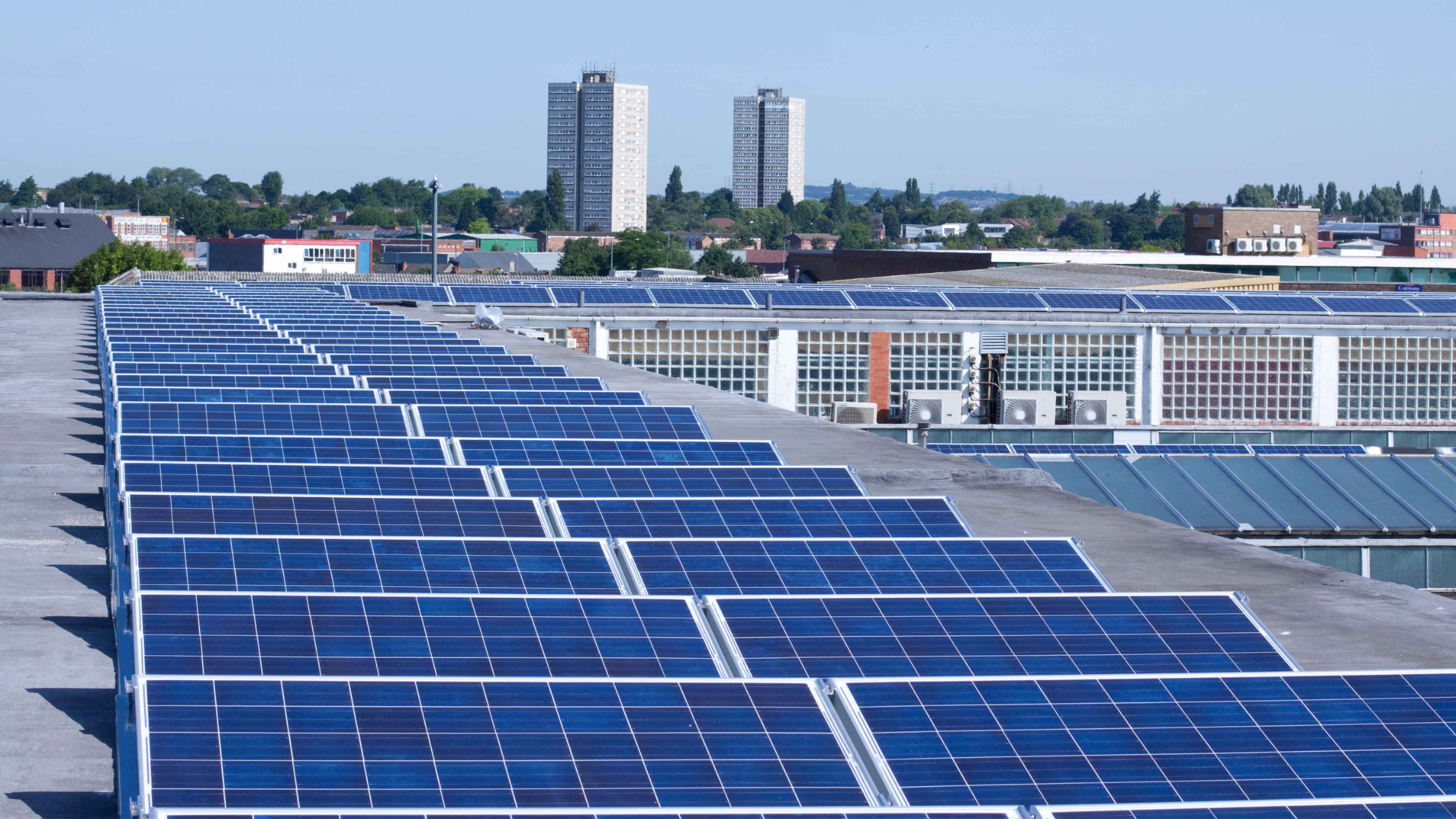 VCT Group rooftop solar panel system in Ontario, Canada. Rooftop with blue solar panels, cityscape in the background with tall buildings and green trees