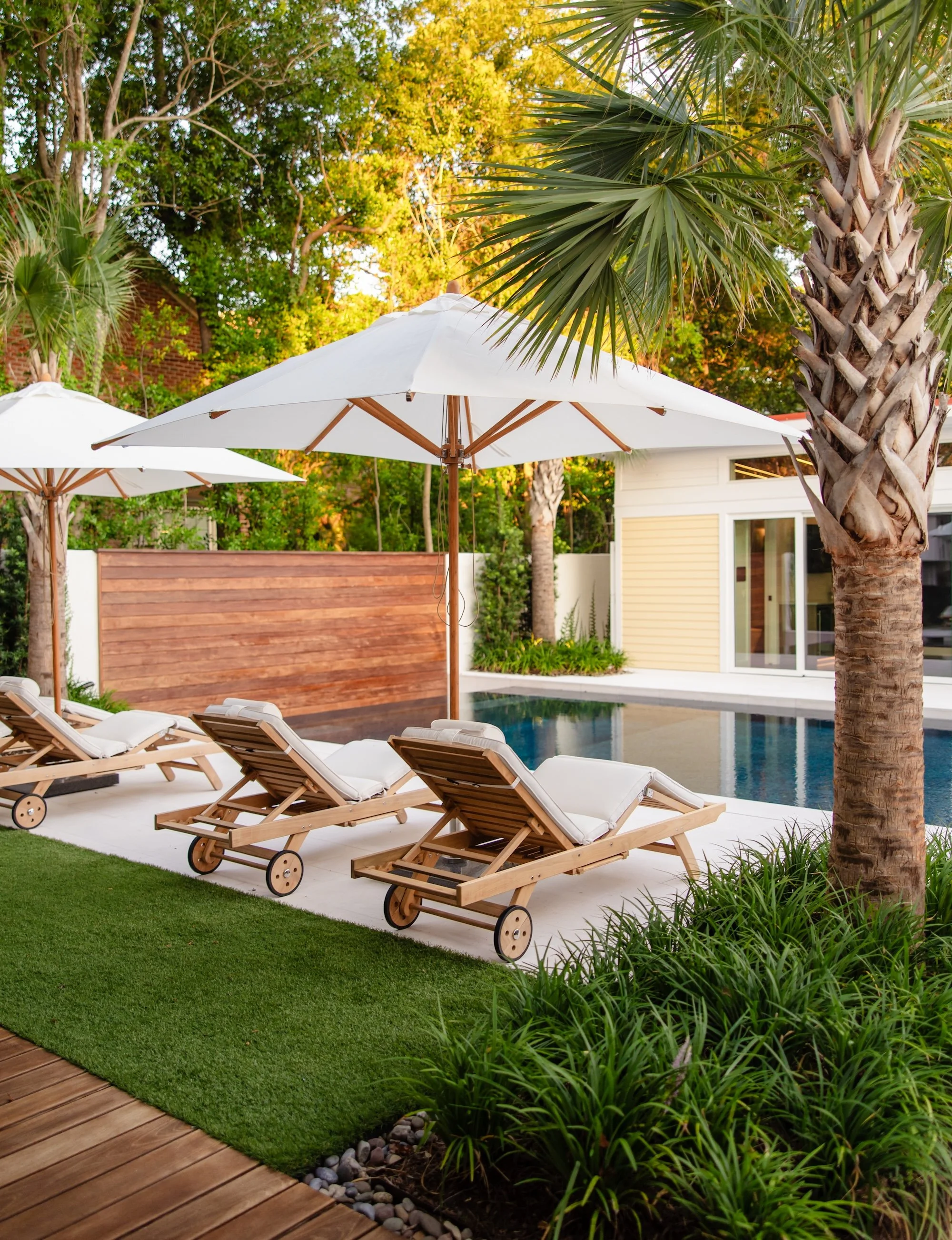 wooden pool loungers beside inground pool with wooden wall in background