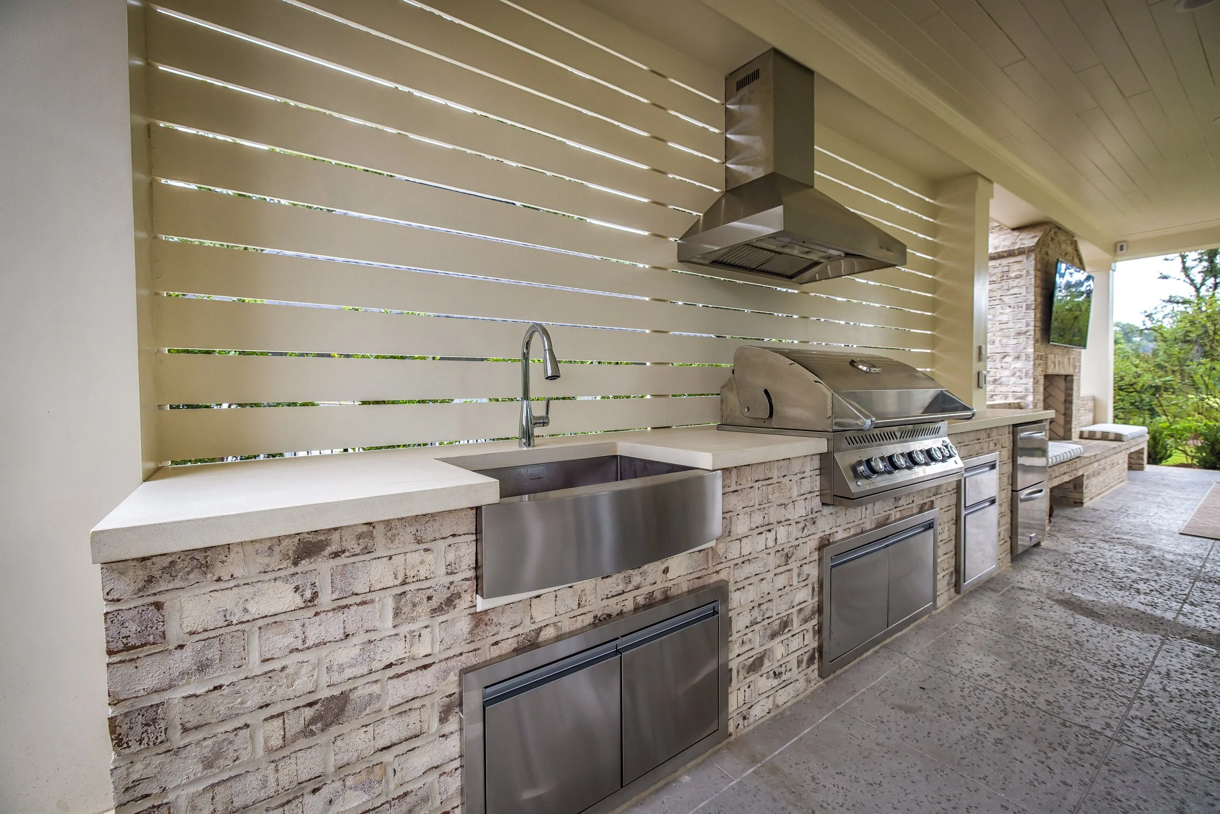 Outdoor kitchen in Landfall, NC with built-in cooking space, stone counters, and connection to an outdoor dining area