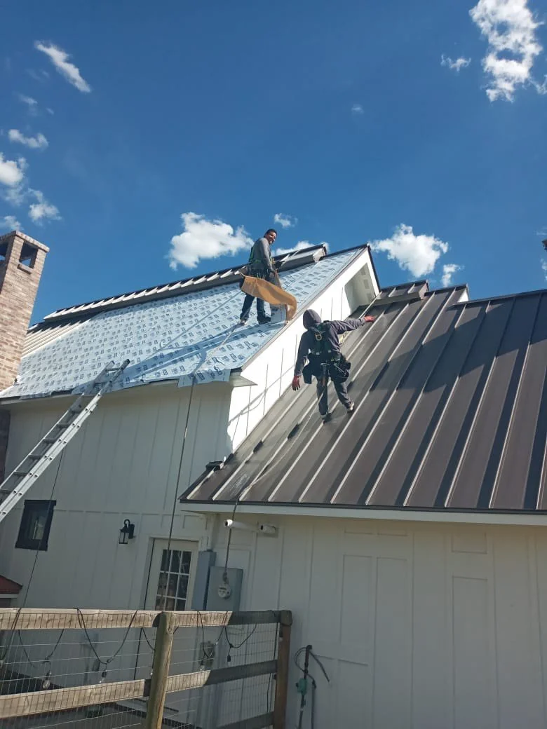 Two workers installing custom metal roof.