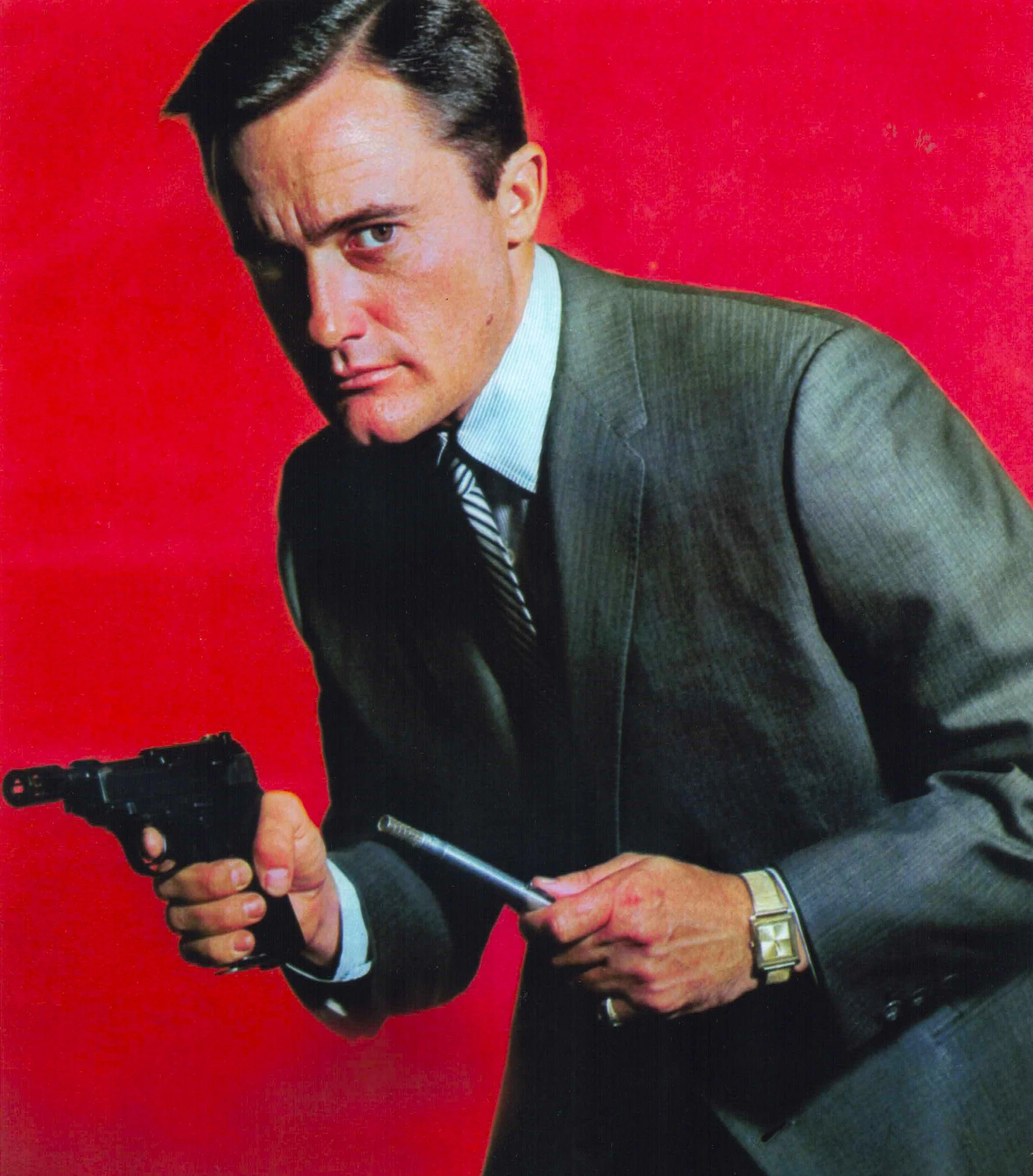 Man in a suit with a gun and a cigarette against a red background.
