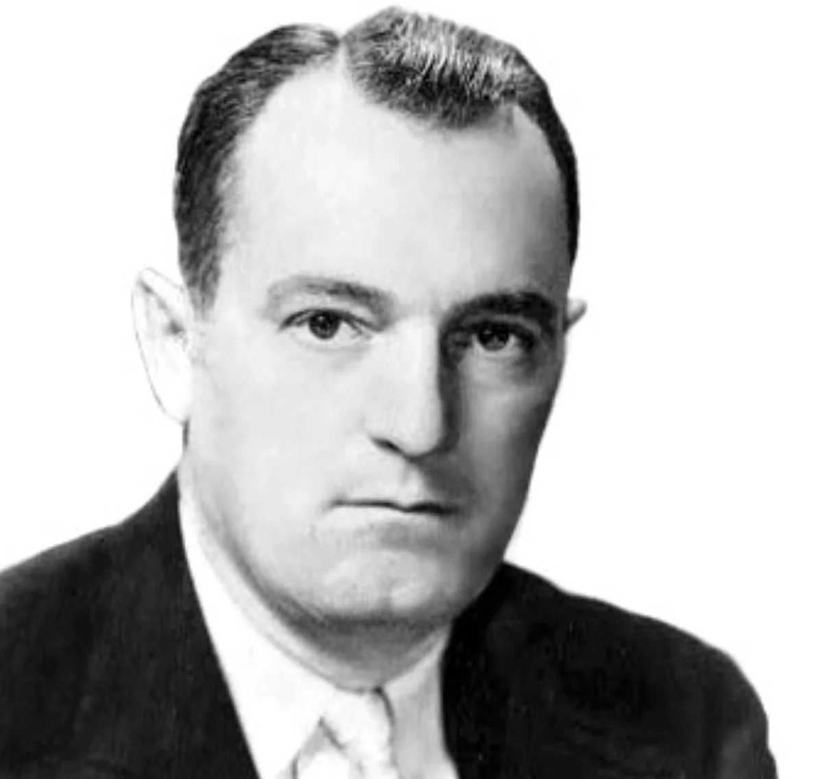 Black and white portrait of a man with slicked-back hair wearing a suit and tie, facing slightly to the right.