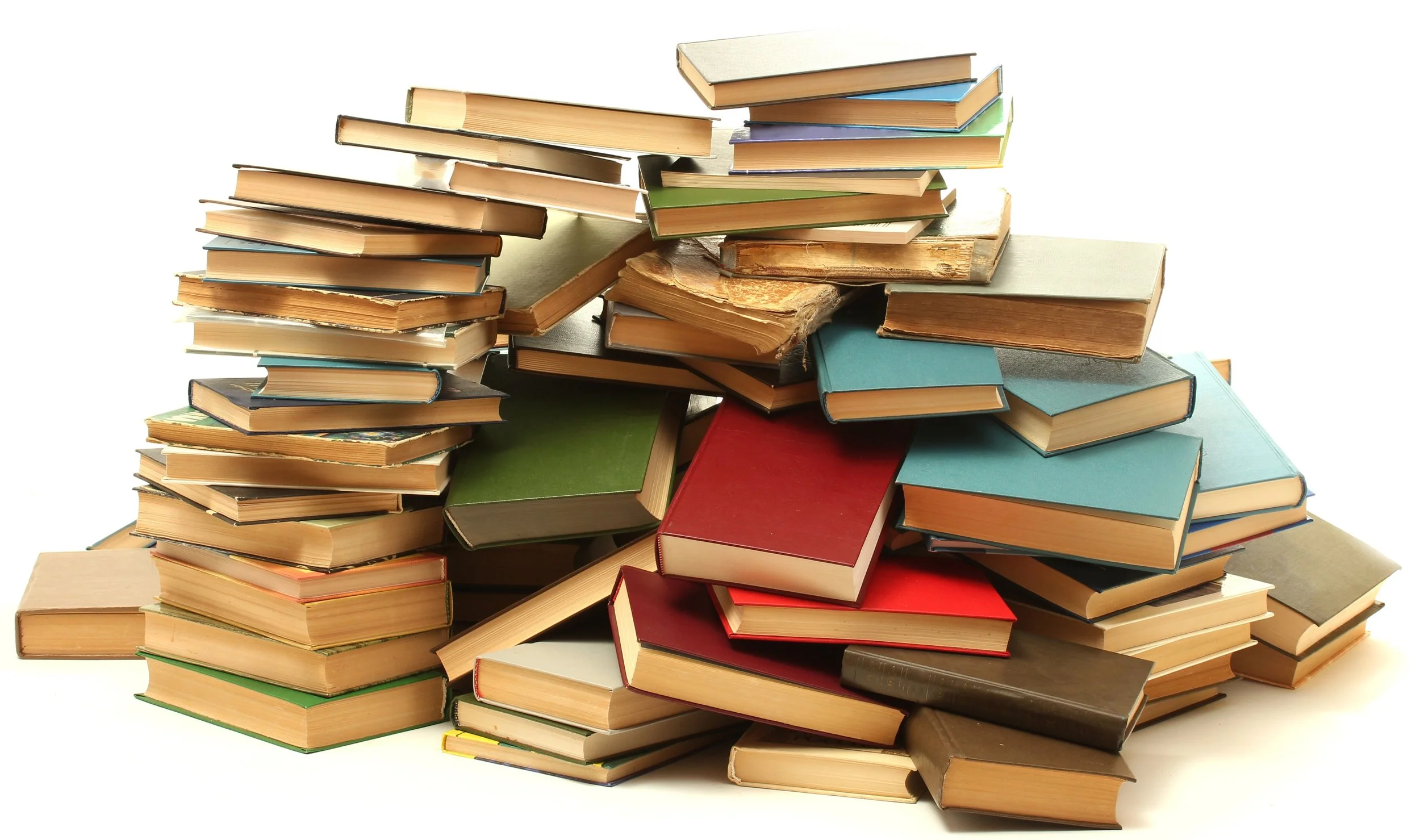 Piles of assorted hardcover and paperback books stacked haphazardly against a white background.
