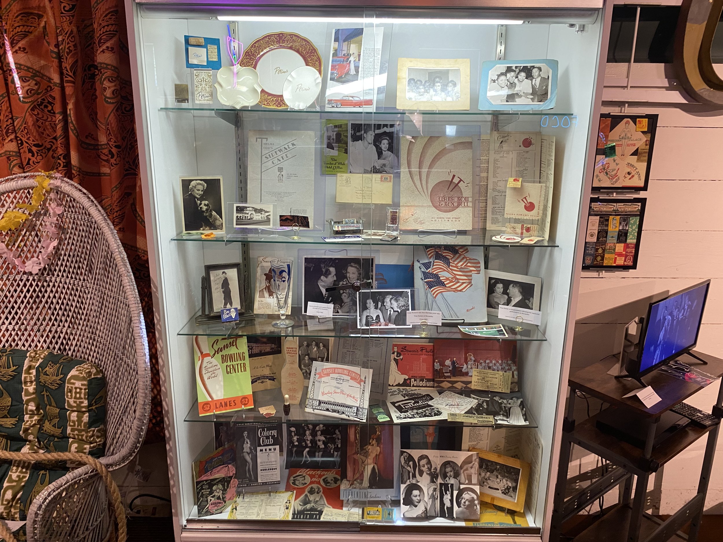 Display case with vintage photographs, memorabilia, and documents, including black-and-white photos of people at events and celebrations, flags, and historical flyers.