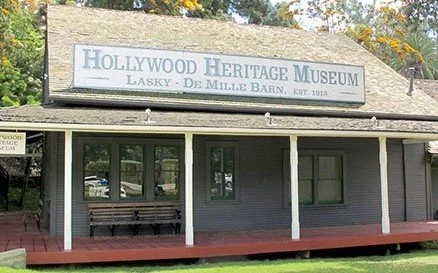 Exterior of the Hollywood Heritage Museum with a sign, a porch, and a bench.