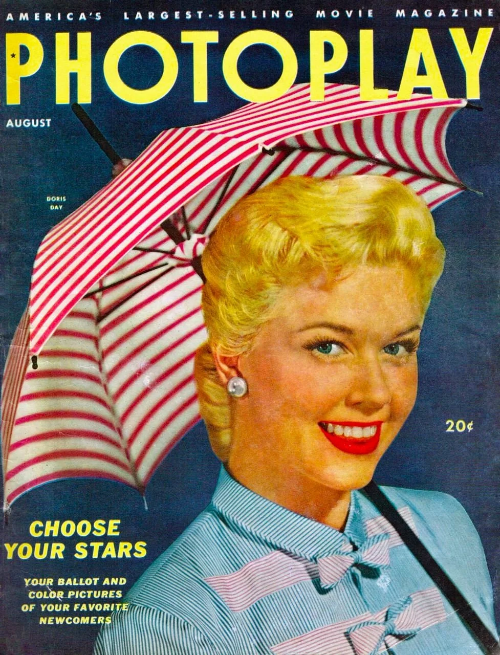 Vintage magazine cover of Photoplay featuring a smiling woman with blonde hair, wearing a striped blouse, holding a red and white striped umbrella over her head.