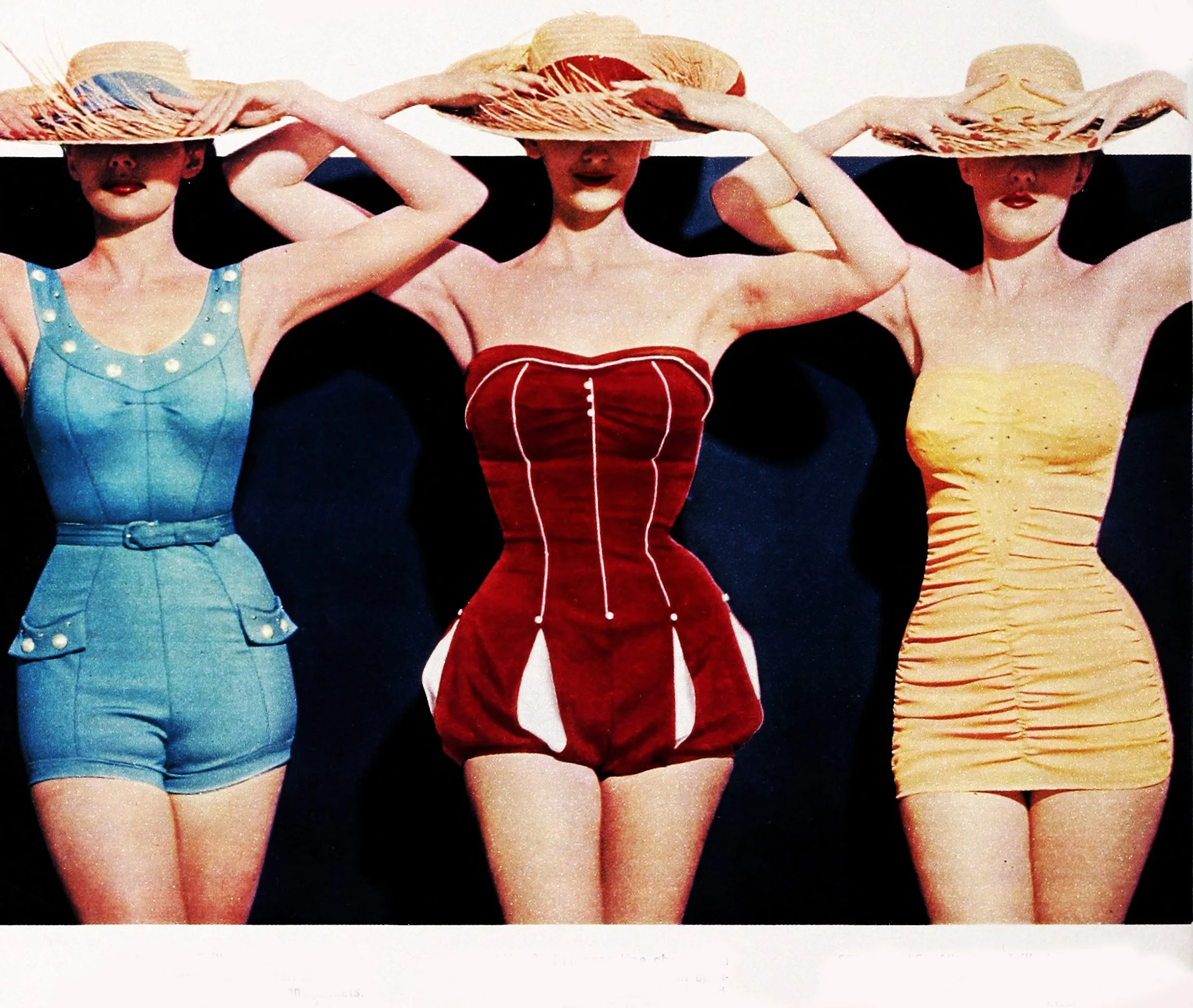Three women wearing vintage swimsuits and wide-brimmed hats, standing with their hands on their hats, against a dark background.