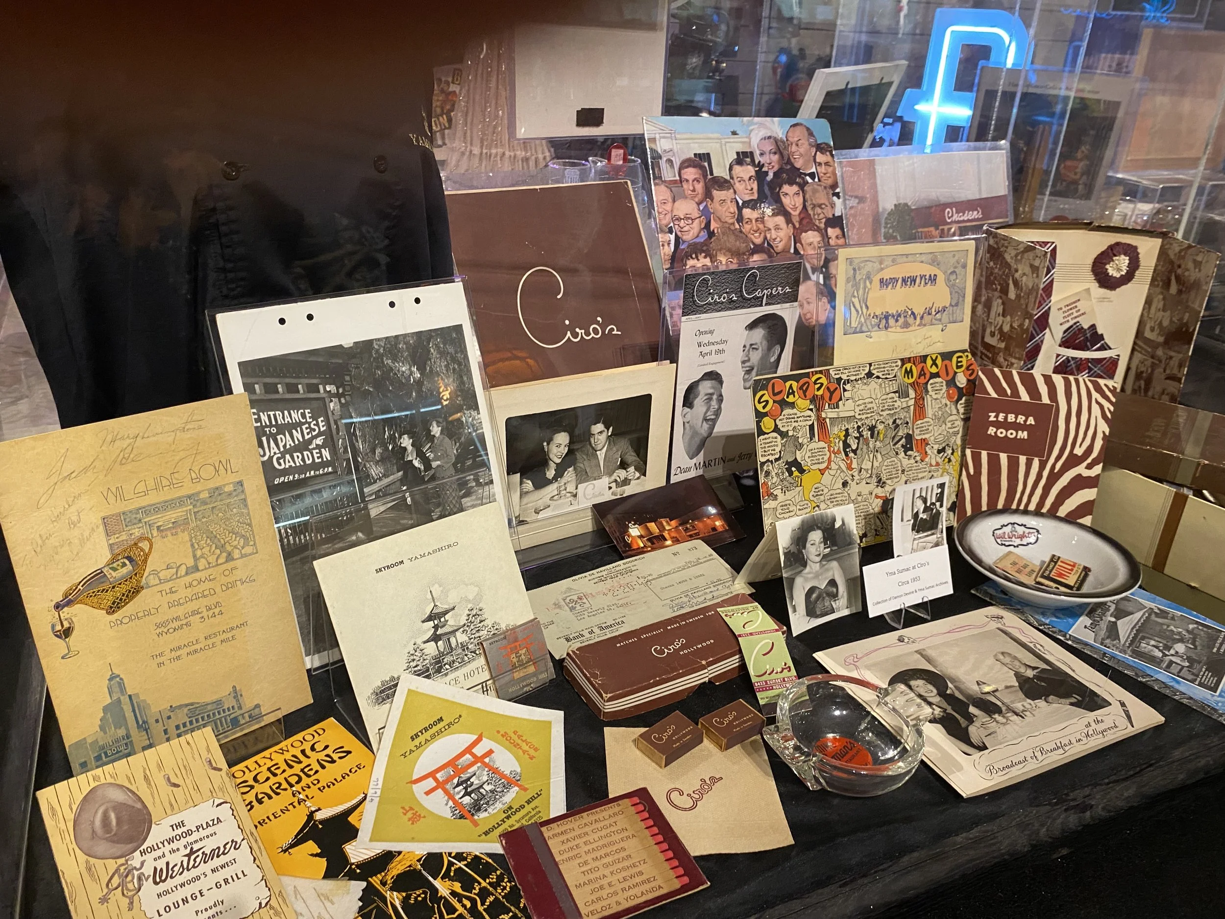 A collection of vintage memorabilia, photographs, promotional materials, and small souvenirs on display at a window showcase.