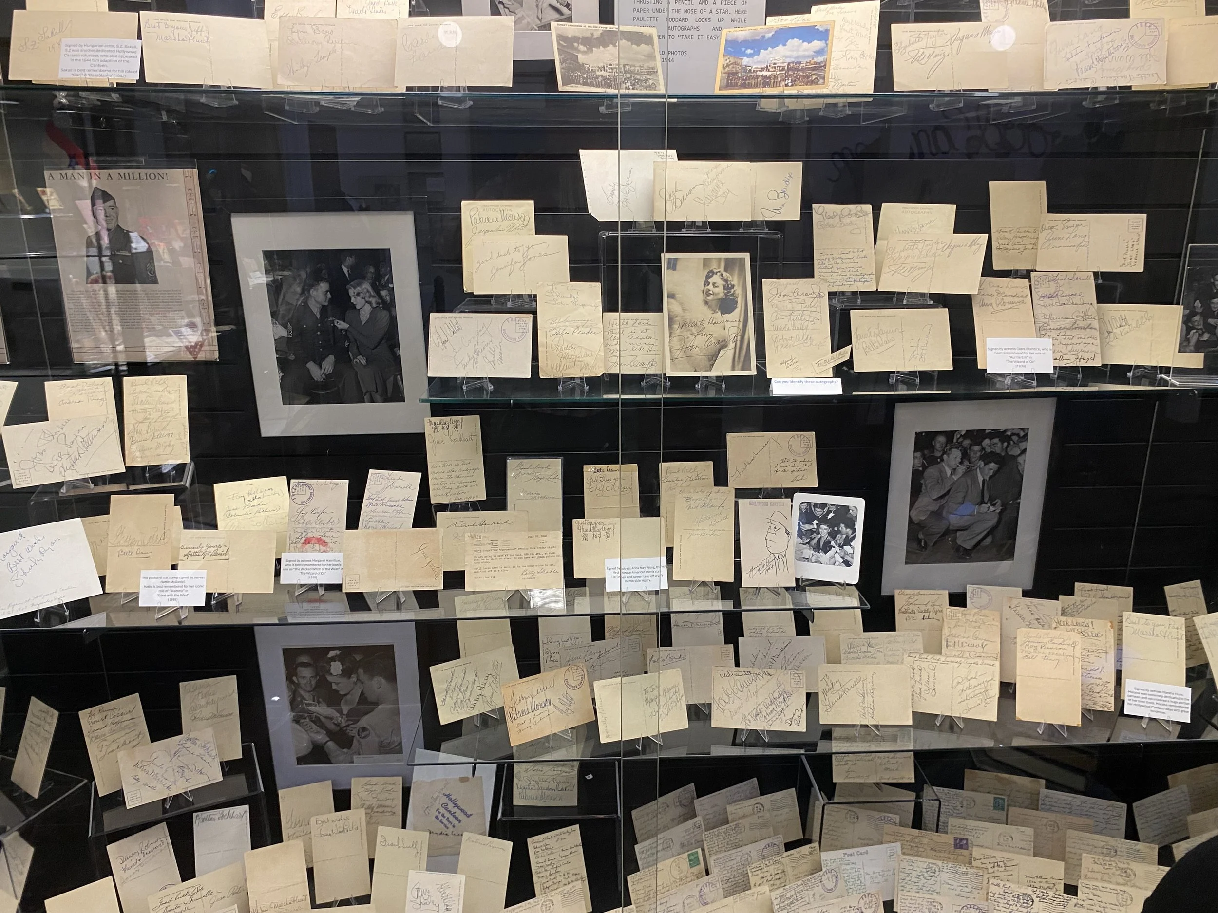 Display case filled with numerous vintage handwritten postcards, photographs, and memorabilia related to Elvis Presley, showcasing a collection of signed items and black-and-white photographs of the musician.