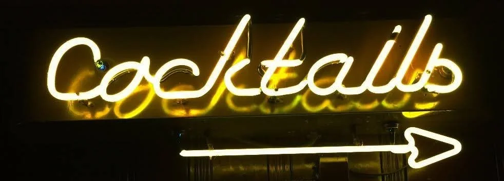 Neon sign reading 'cocktails' with a right arrow pointing to the right.