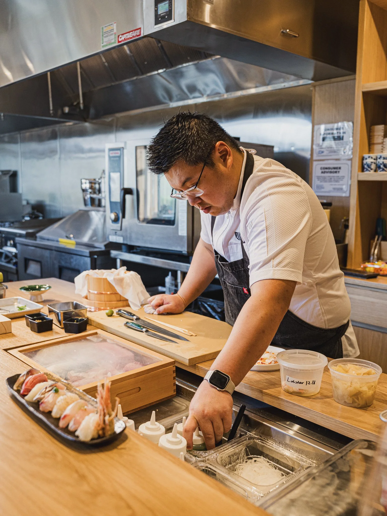 Chef David Tsan preparing an omakase course at the chef's counter, featured in the Orlando Bungalower article about his O-Town West restaurant.