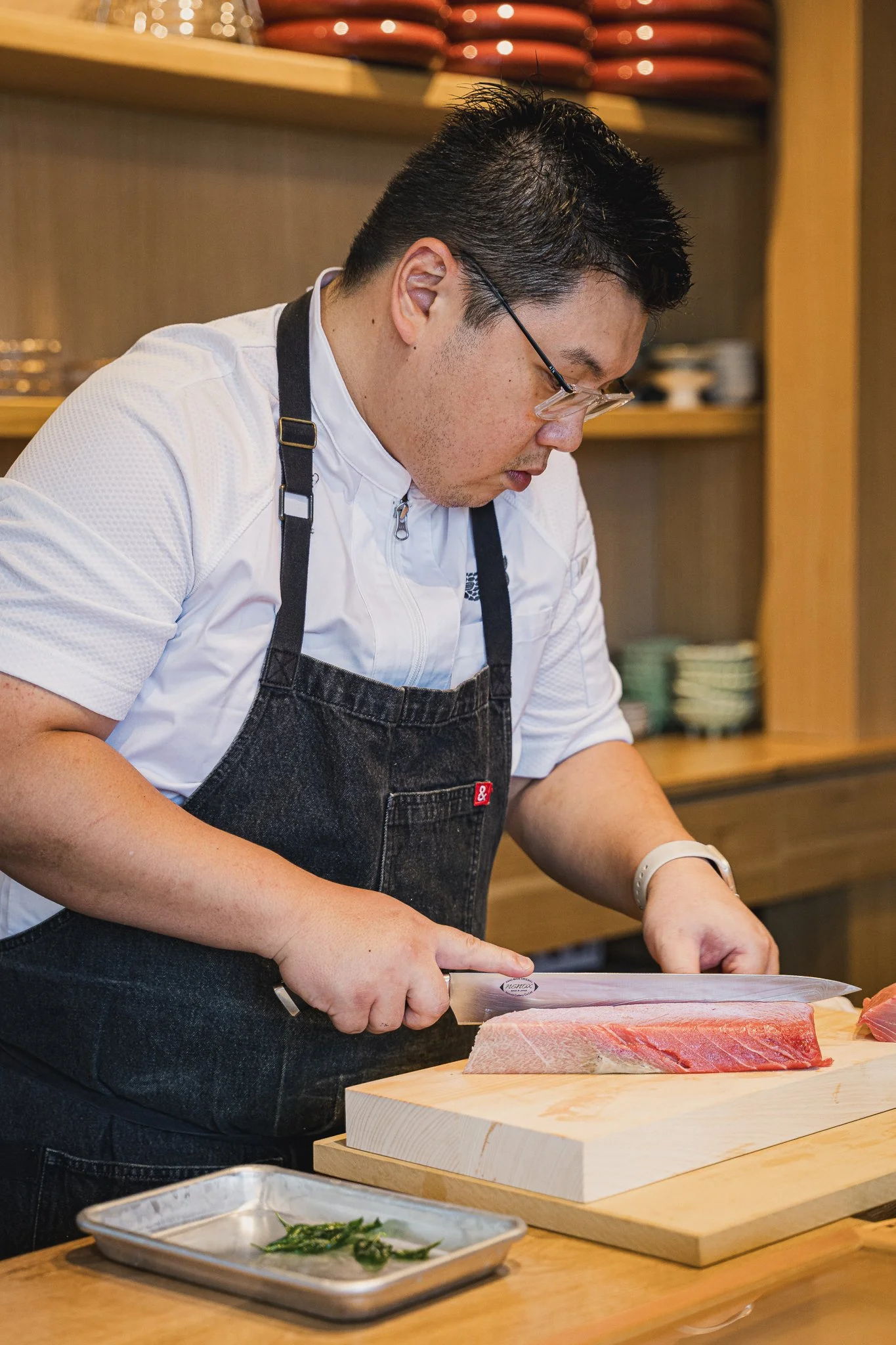 Chef David Tsan using a professional Japanese knife to slice premium Bluefin Tuna at the Kappo Tsan sushi counter.