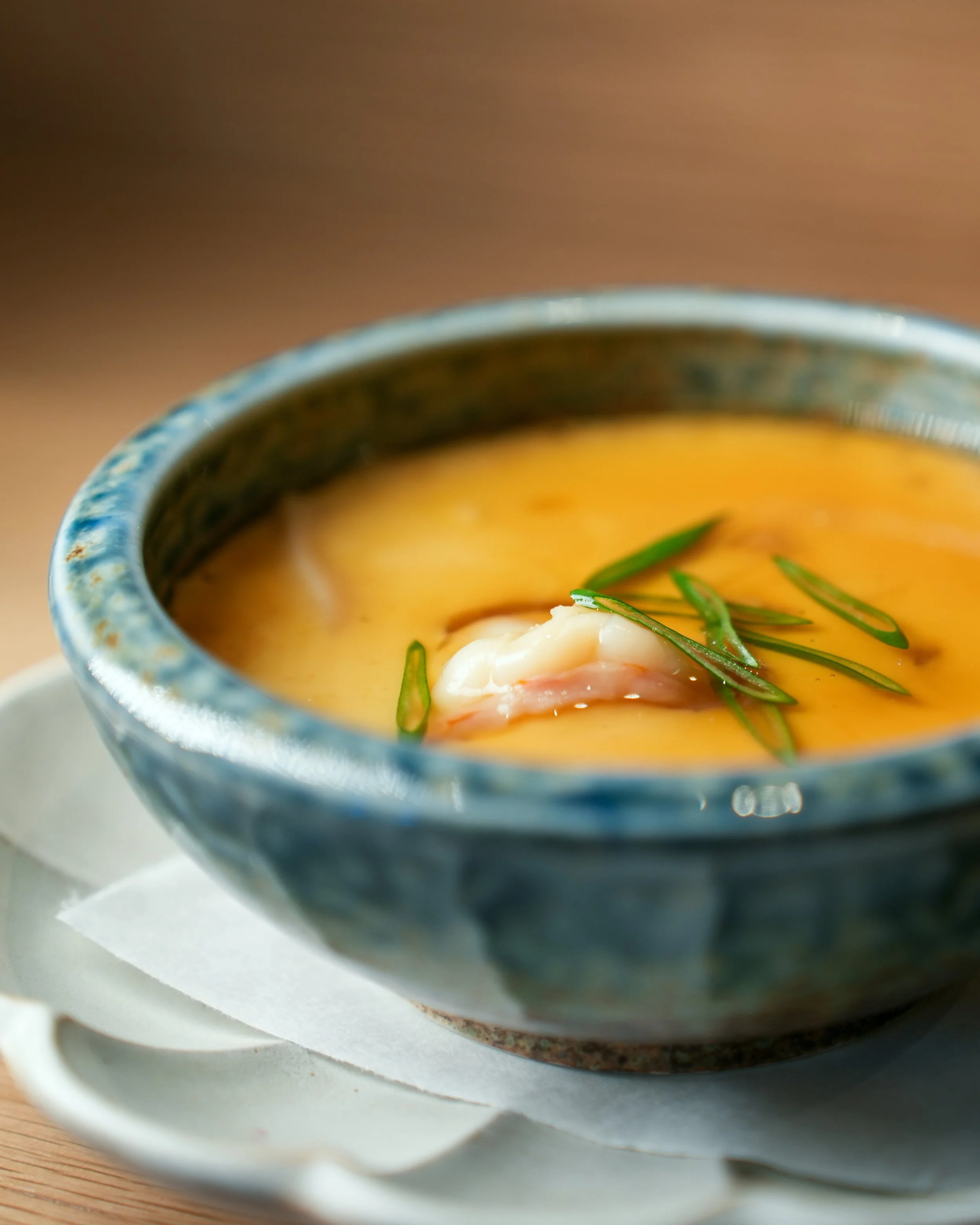 Traditional Japanese Chawanmushi savory egg custard topped with shrimp and scallions in a blue ceramic bowl.
