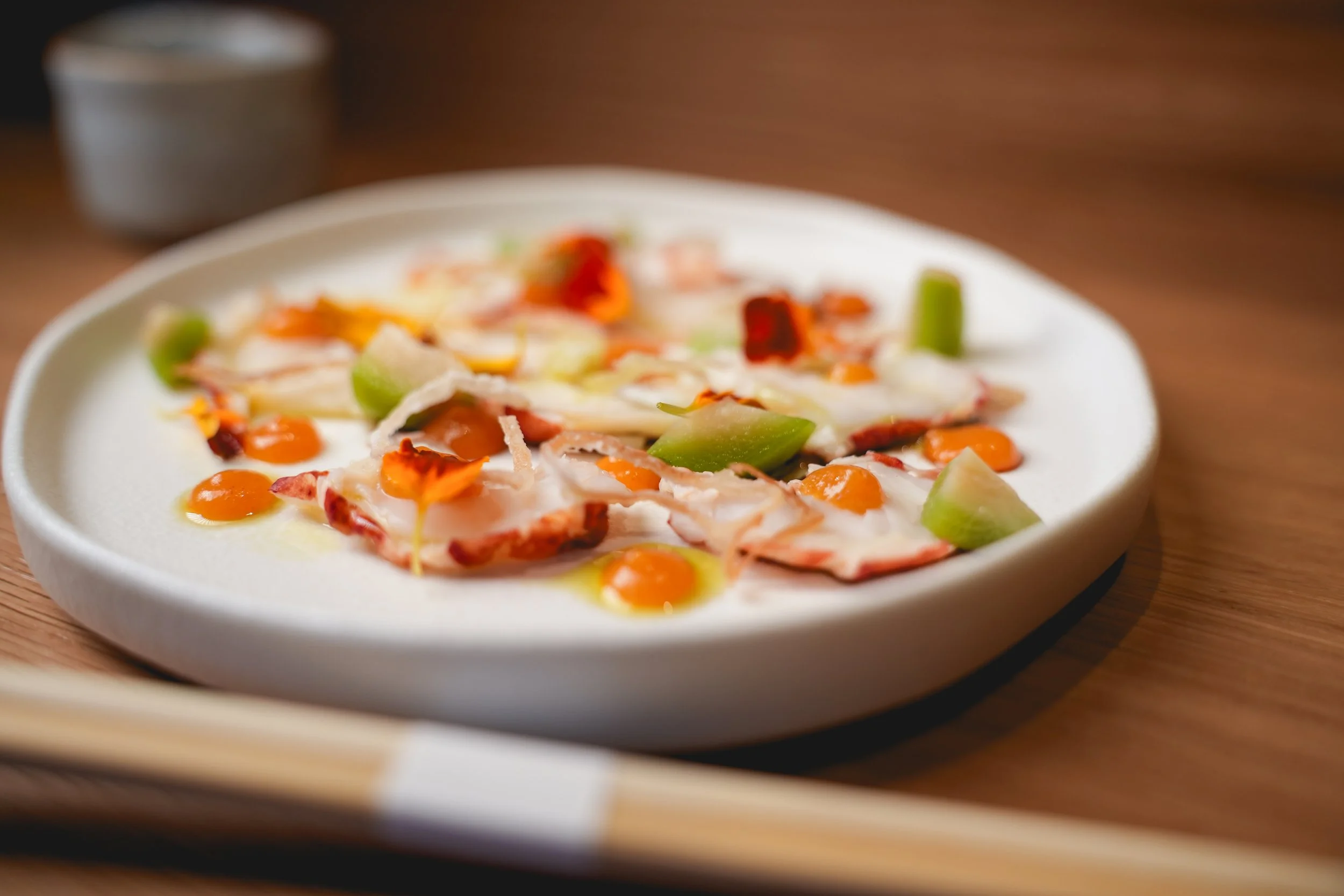 Thinly sliced octopus carpaccio with edible flowers and citrus gel, representing the modern Taiwanese-Japanese fusion at Kappo Tsan.