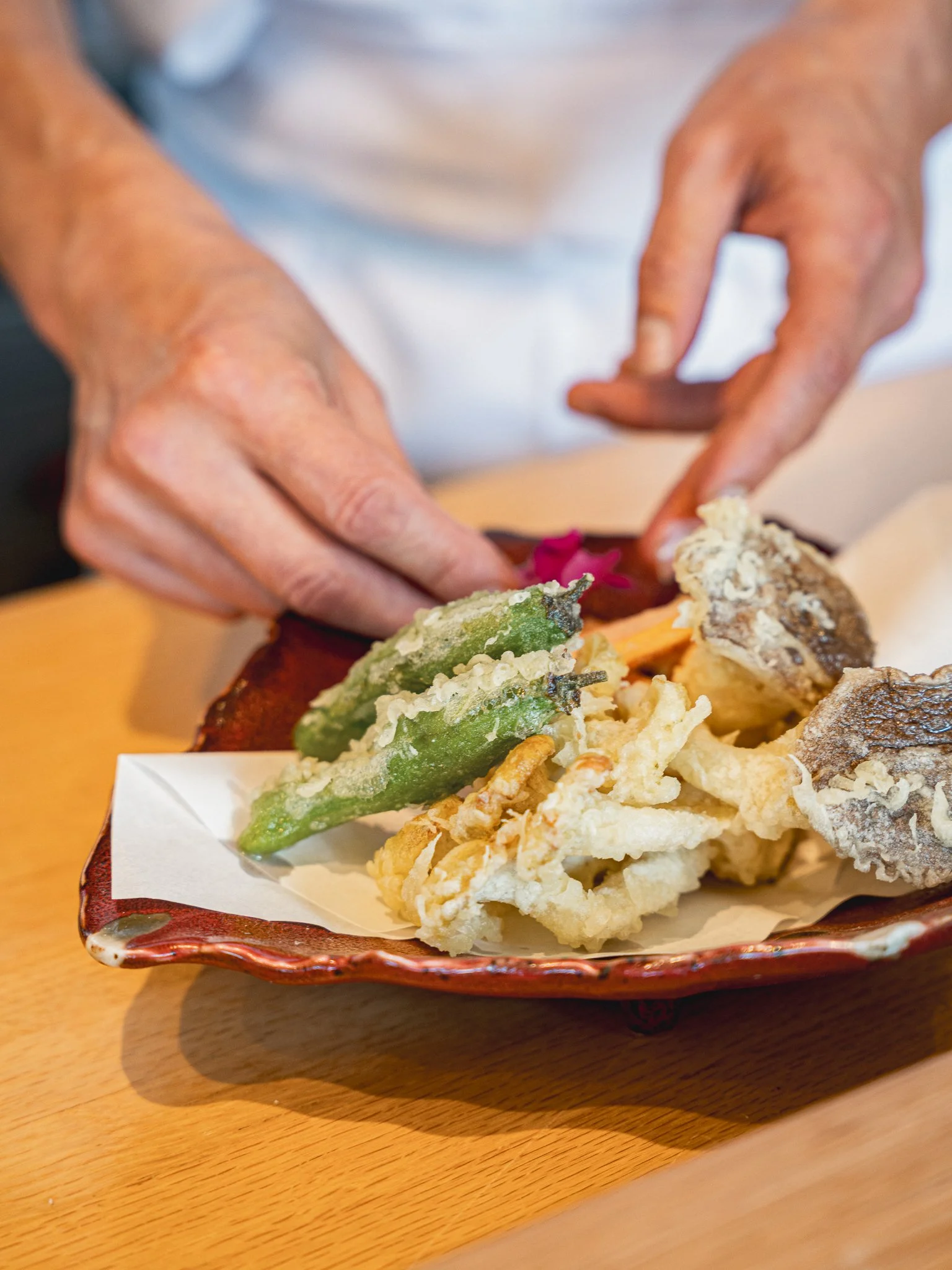 Chef plating crispy seasonal vegetable tempura, showcasing the hot-course variety of a Kappo-style meal.