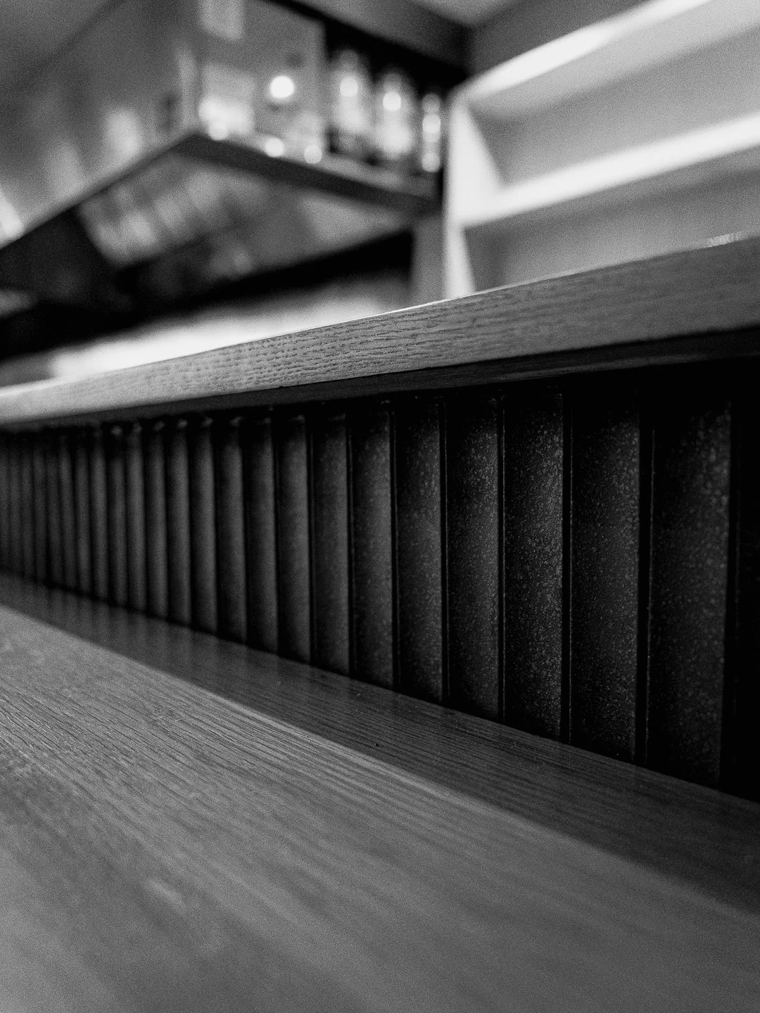 A minimalist wooden sushi counter and dark textured bar front at Kappo Tsan’s intimate 8-seat dining room in Lake Buena Vista.