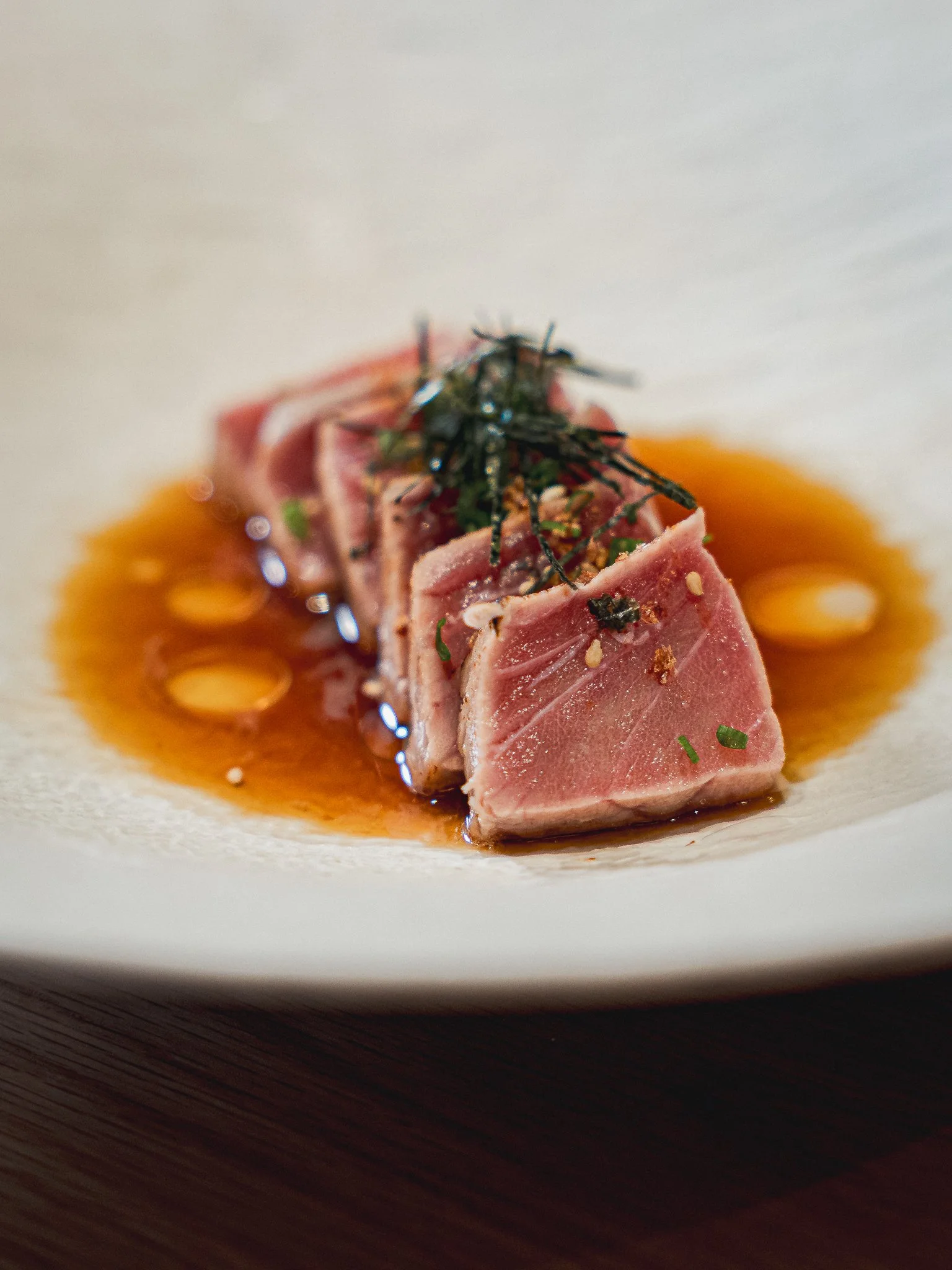A seared tuna tataki dish with delicate garnish and citrus soy reduction, part of the seasonal kaiseki menu at Kappo Tsan.