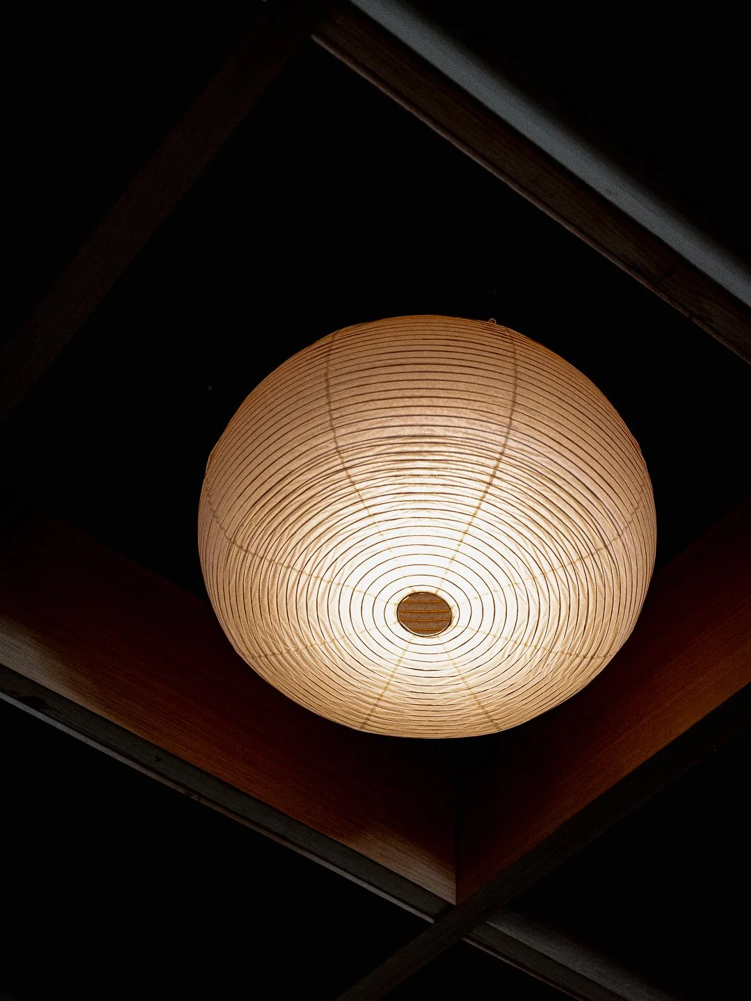 A traditional round Japanese paper lantern providing soft, warm ambient lighting in the Kappo Tsan dining room.