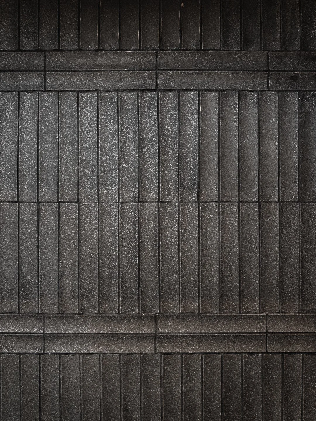 Textured dark grey architectural wall tiles at Kappo Tsan restaurant, reflecting a modern and minimalist Japanese aesthetic.