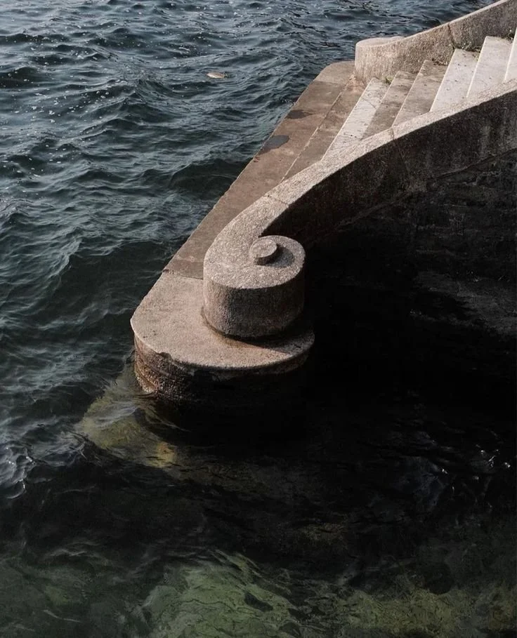 Concrete staircase extending into the water, with waves on the lake or ocean surface.
