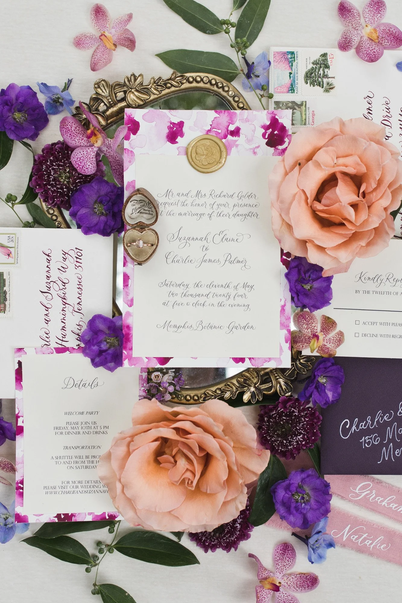 Wedding invitation surrounded by pink and purple flowers, green leaves, and stamps.