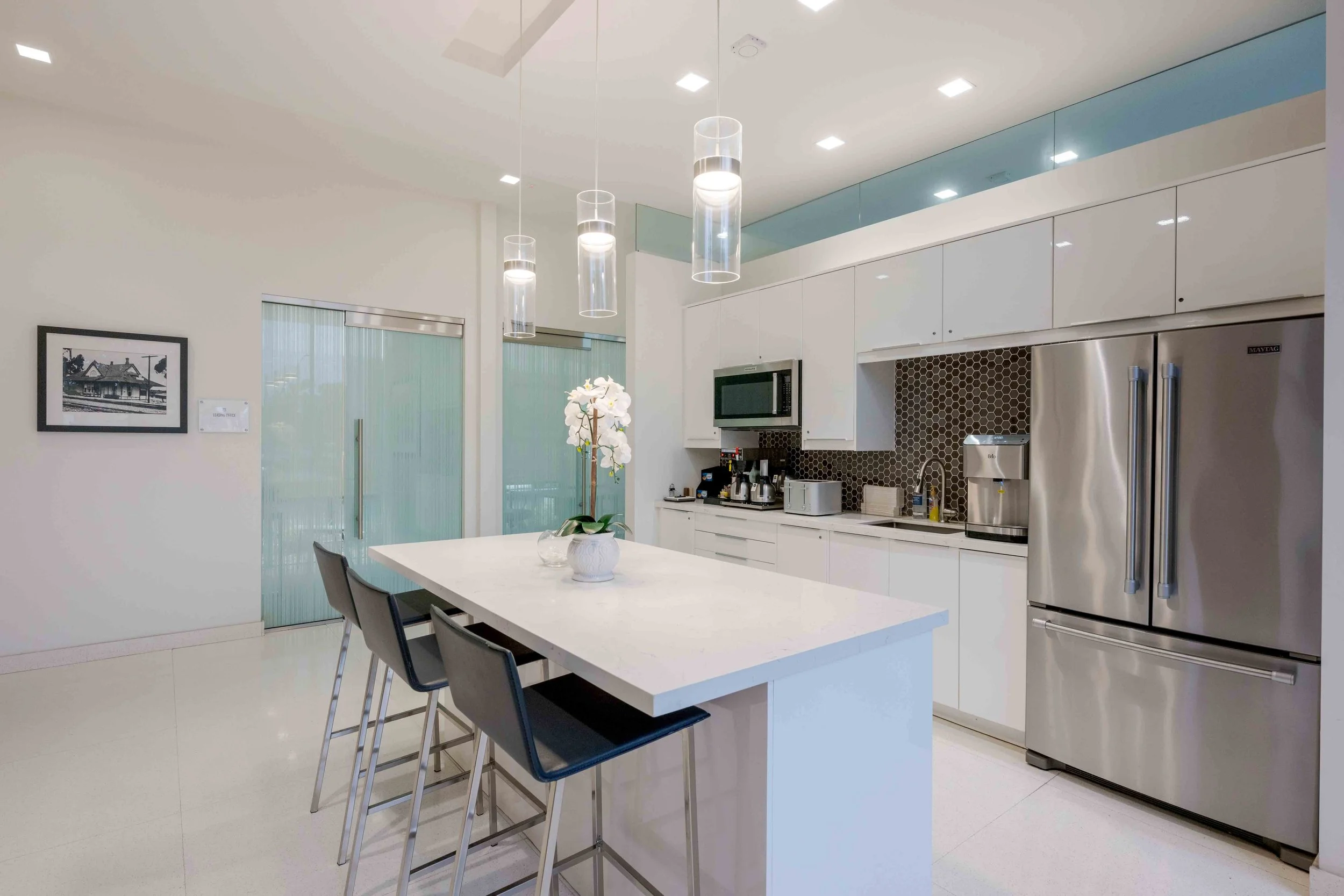 Large office kitchen with an island, refrigerator, coffee maker, toaster and microwave