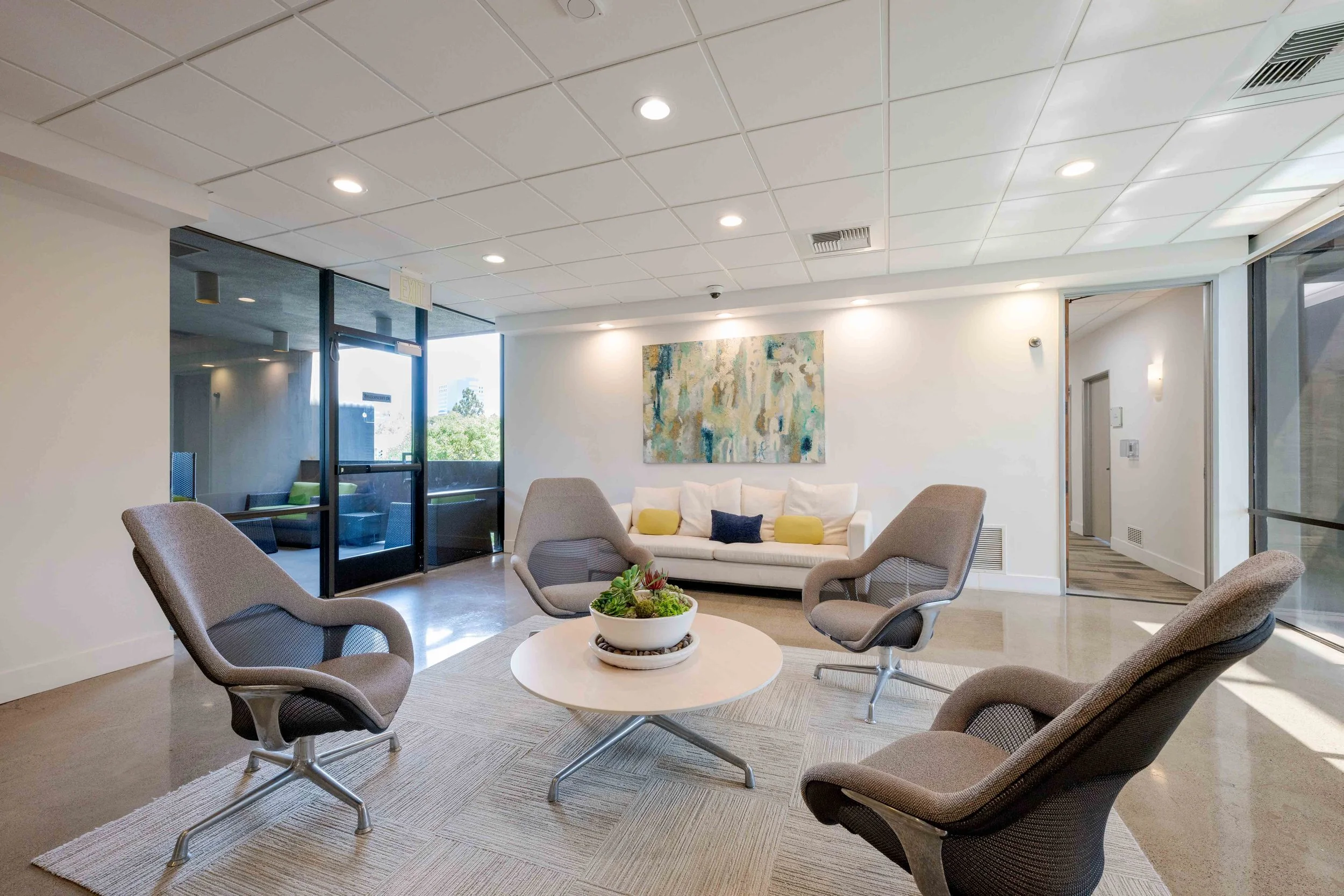 Office seating area with chairs and a large couch against a wall.