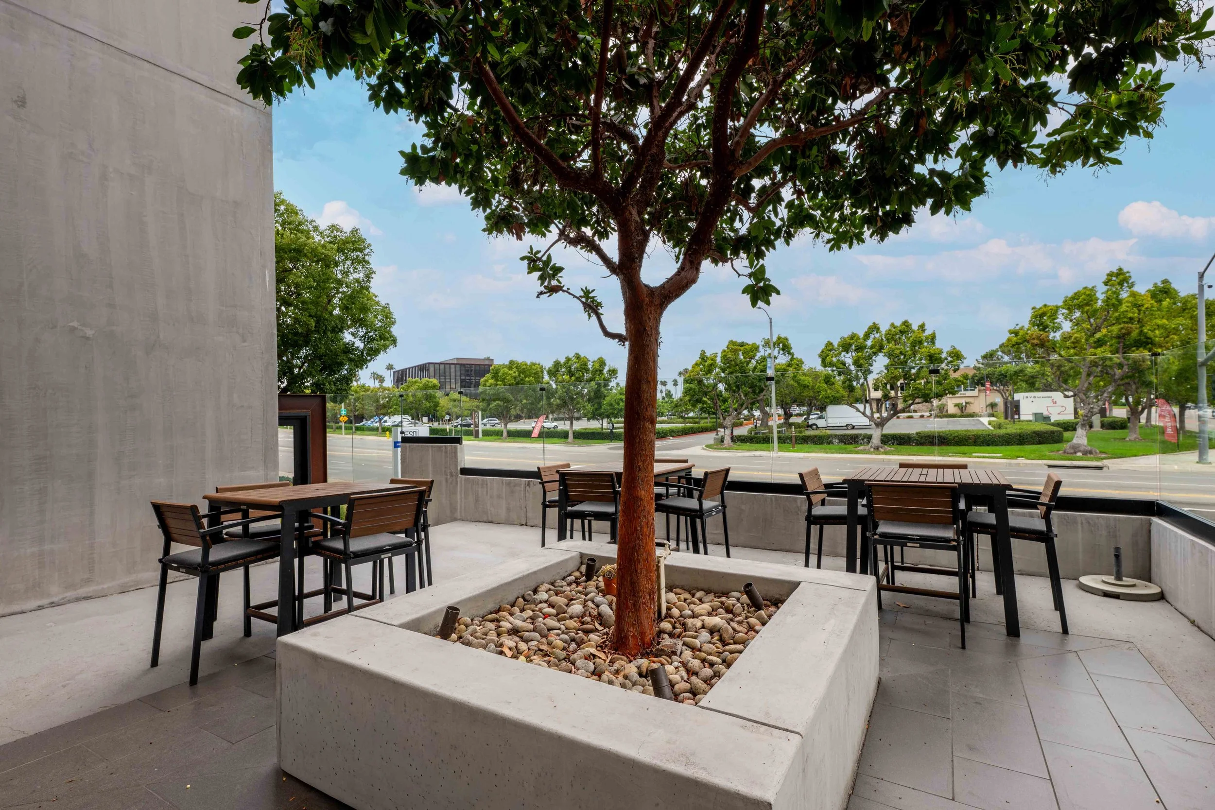 Outdoor patio space with multiple seating areas with a large tree in the middle