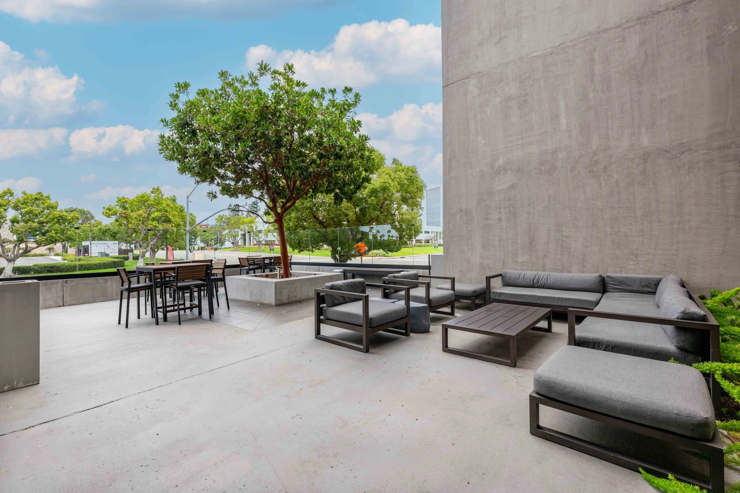 Outdoor patio area with plenty of seating and a large tree in the middle