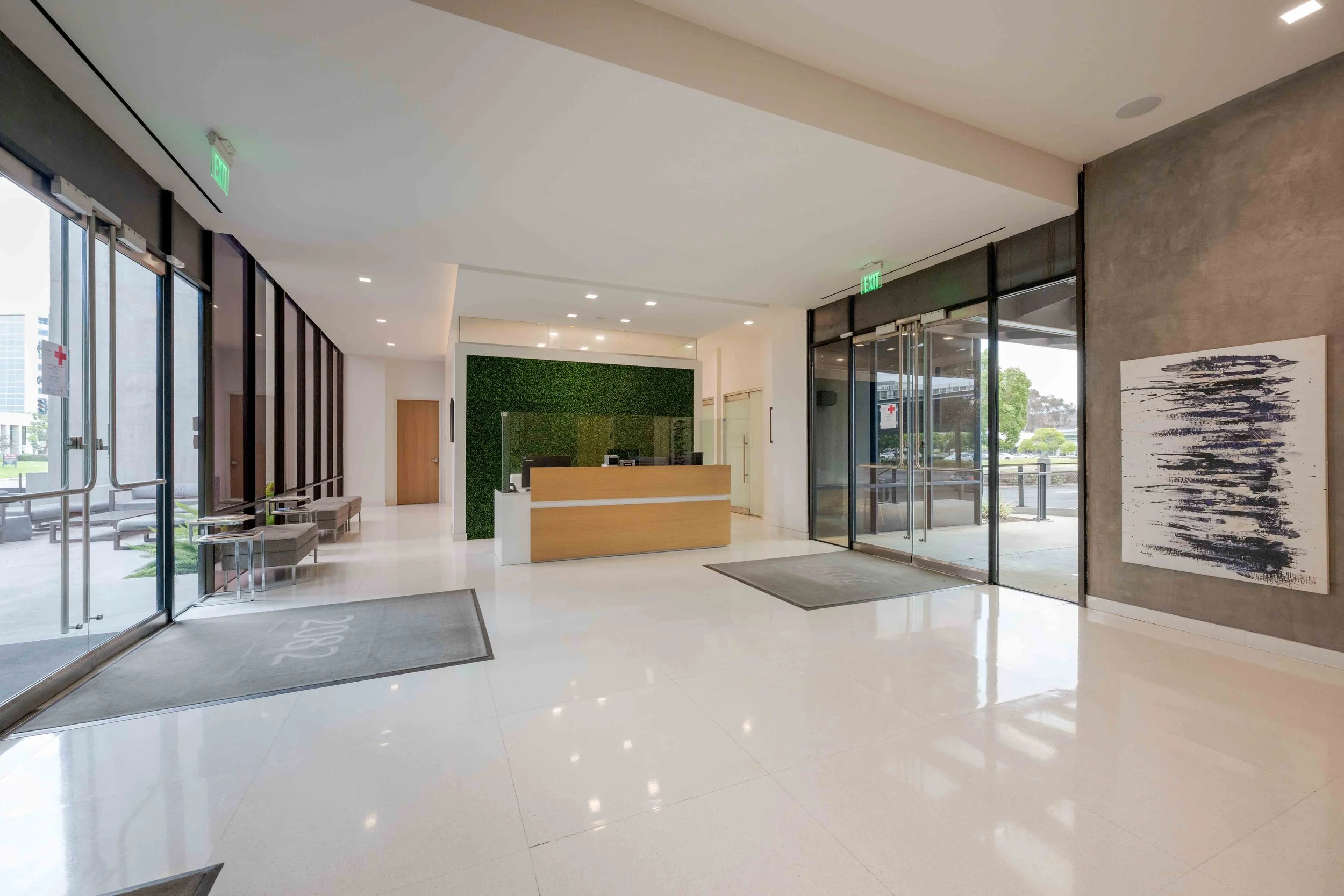Front lobby with white floors and a front desk with a green wall behind