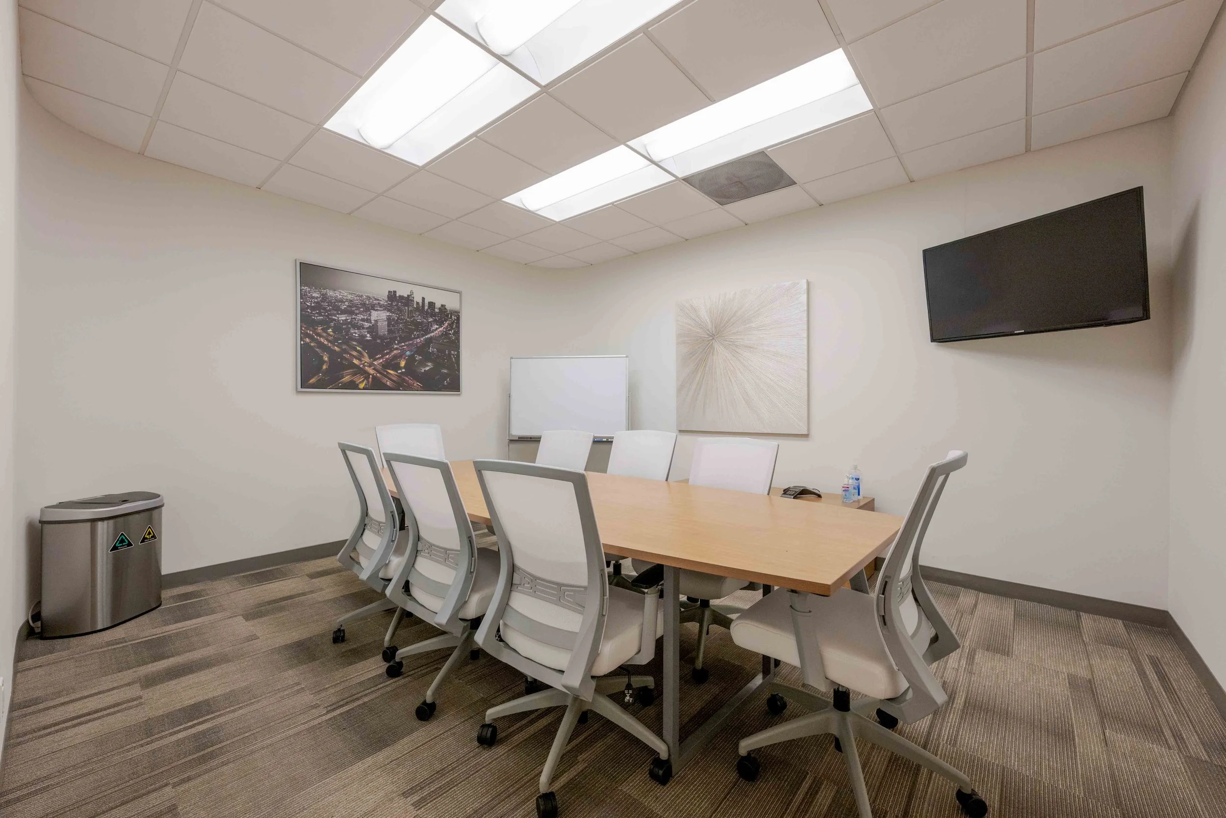 A private meeting room with a large conference table and a screen on the wall