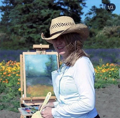 A color photo of the artist, as she paints en plein air in the lavender fields on Whidbey Island, WA