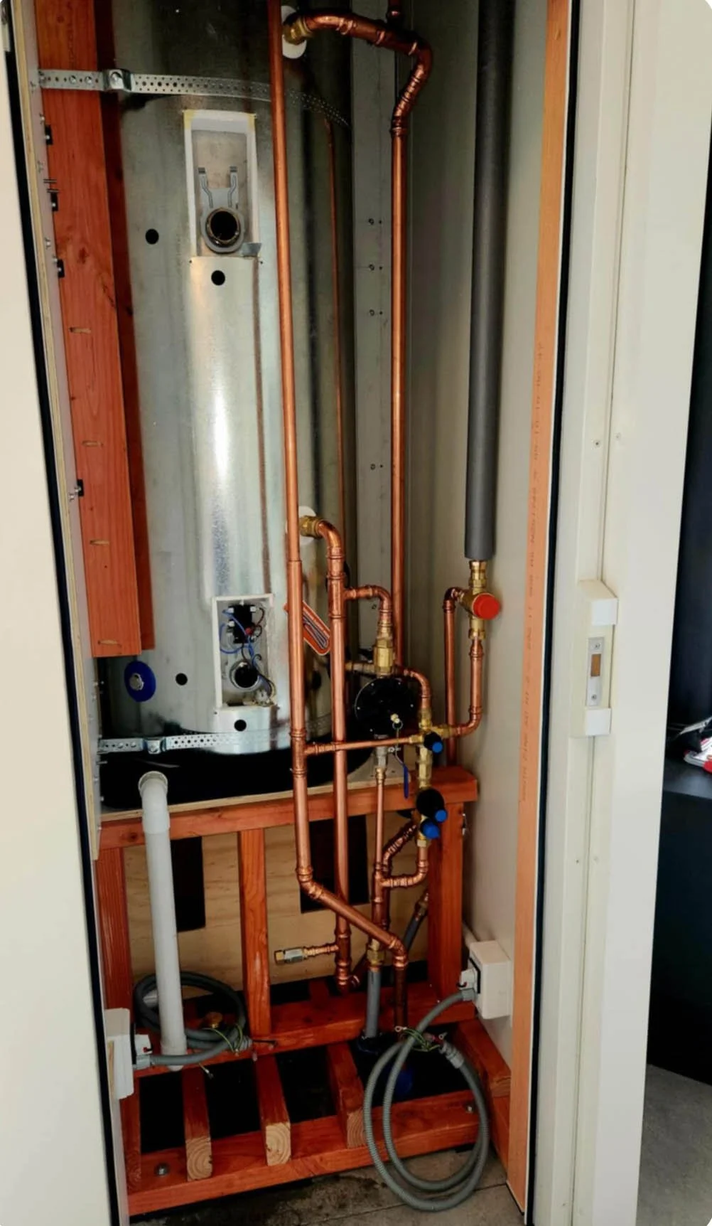 Interior of a mechanical room showing copper pipes and heating system components.