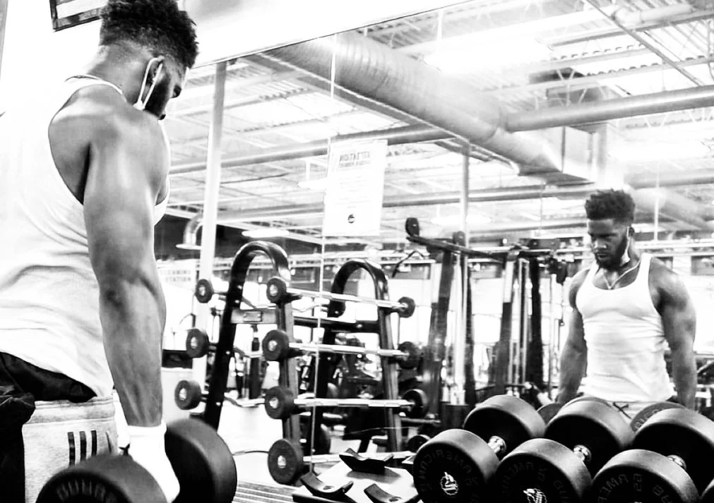 Two men lifting dumbbells in a gym.