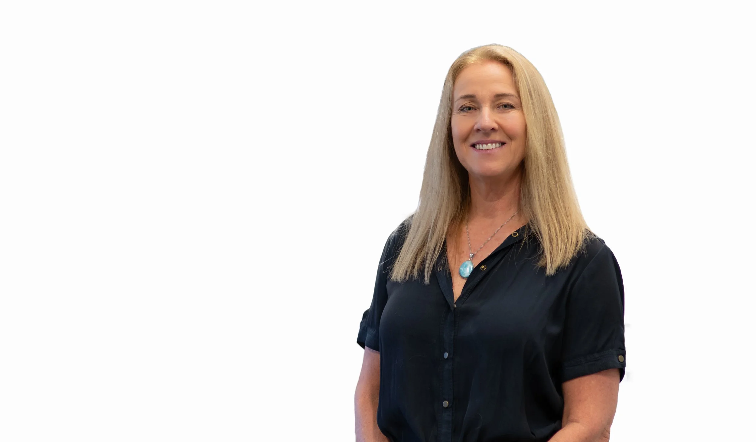 Woman with blonde hair, wearing a black shirt and a blue pendant necklace, smiling, against a plain white background.