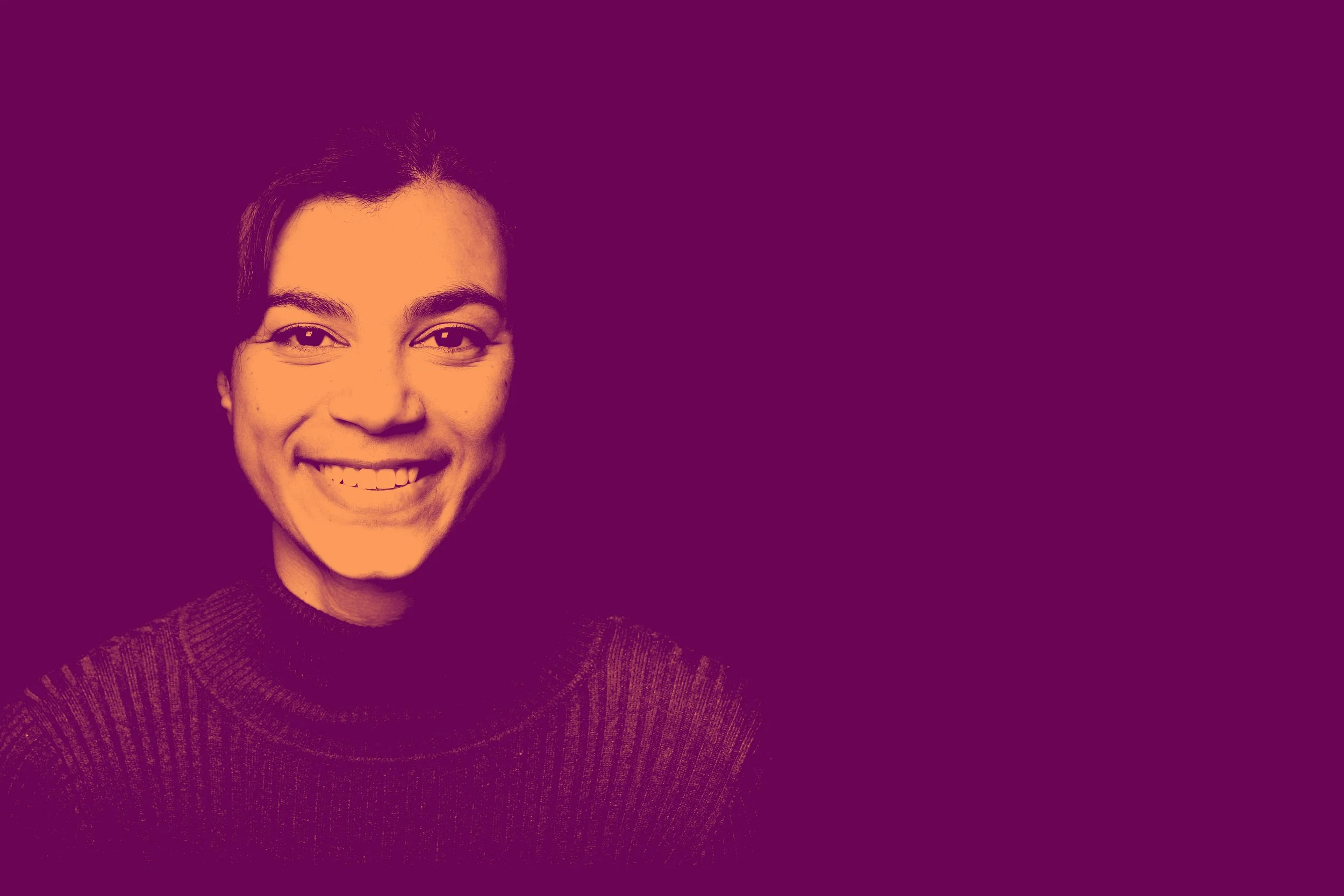 A young woman with dark hair, smiling, wearing a dark turtleneck sweater, against a purple background.