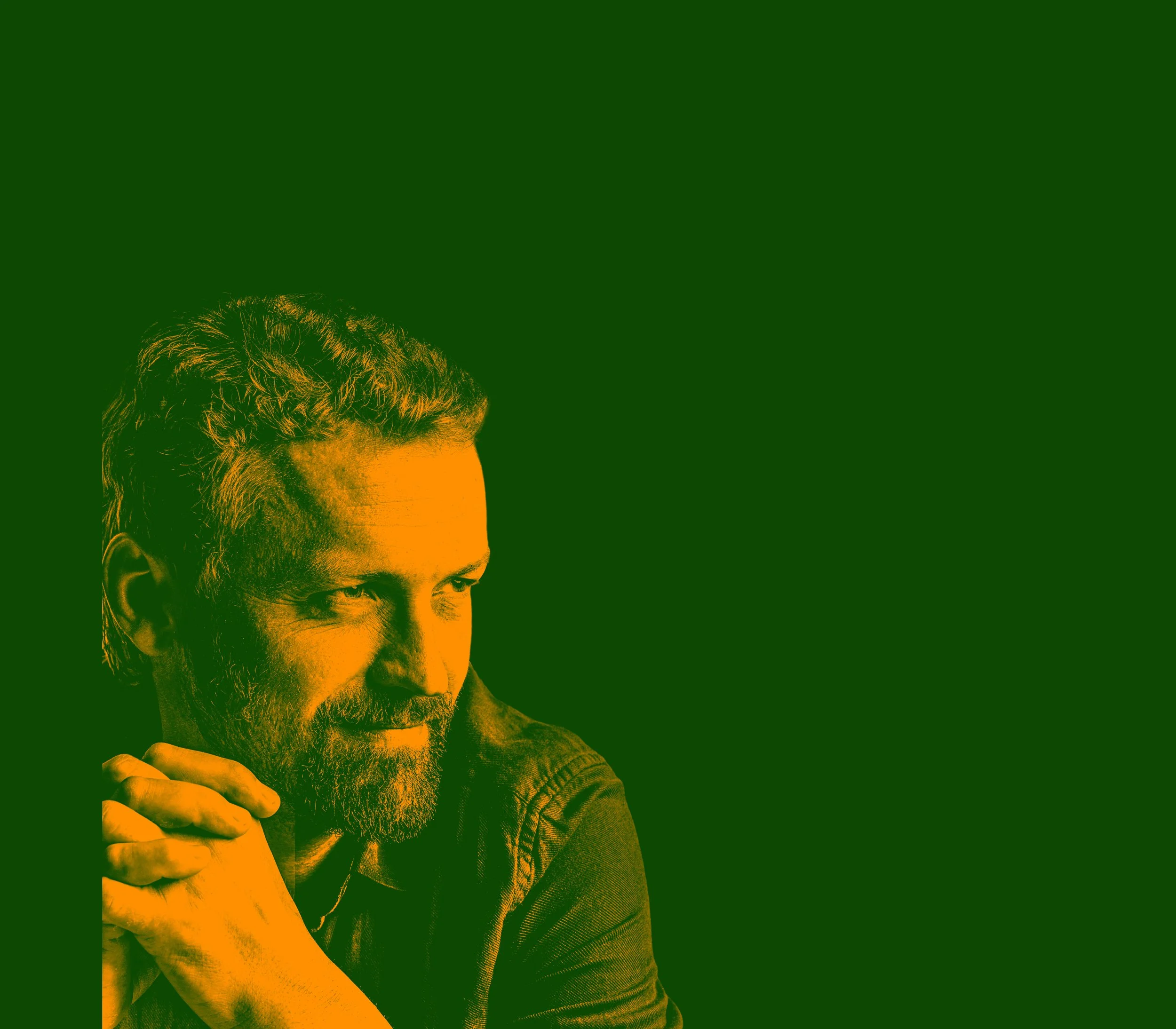 Portrait of a man with a beard, looking contemplative, with hands clasped, against a green and orange stylized background.