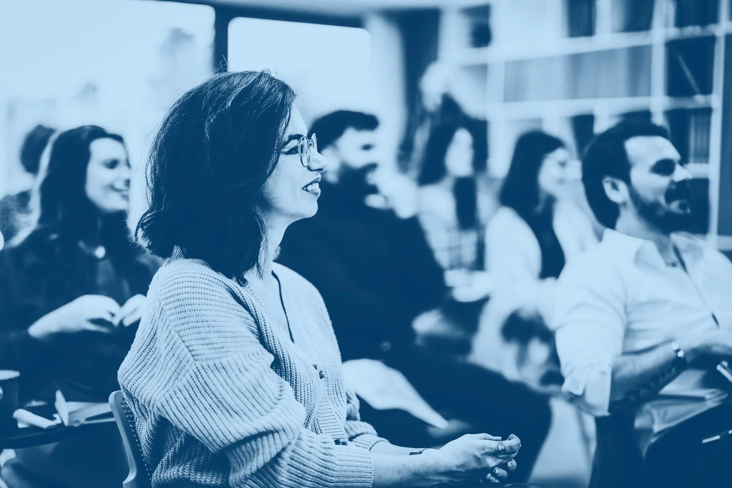 A group of people attending a conference or seminar, seated in rows and paying attention.