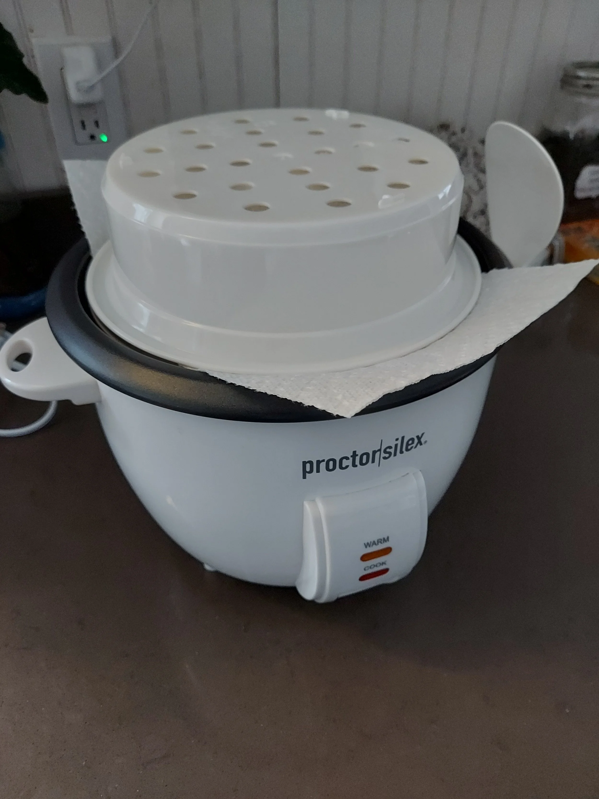 Image of electric rice cooker with steamer basket inverted on top