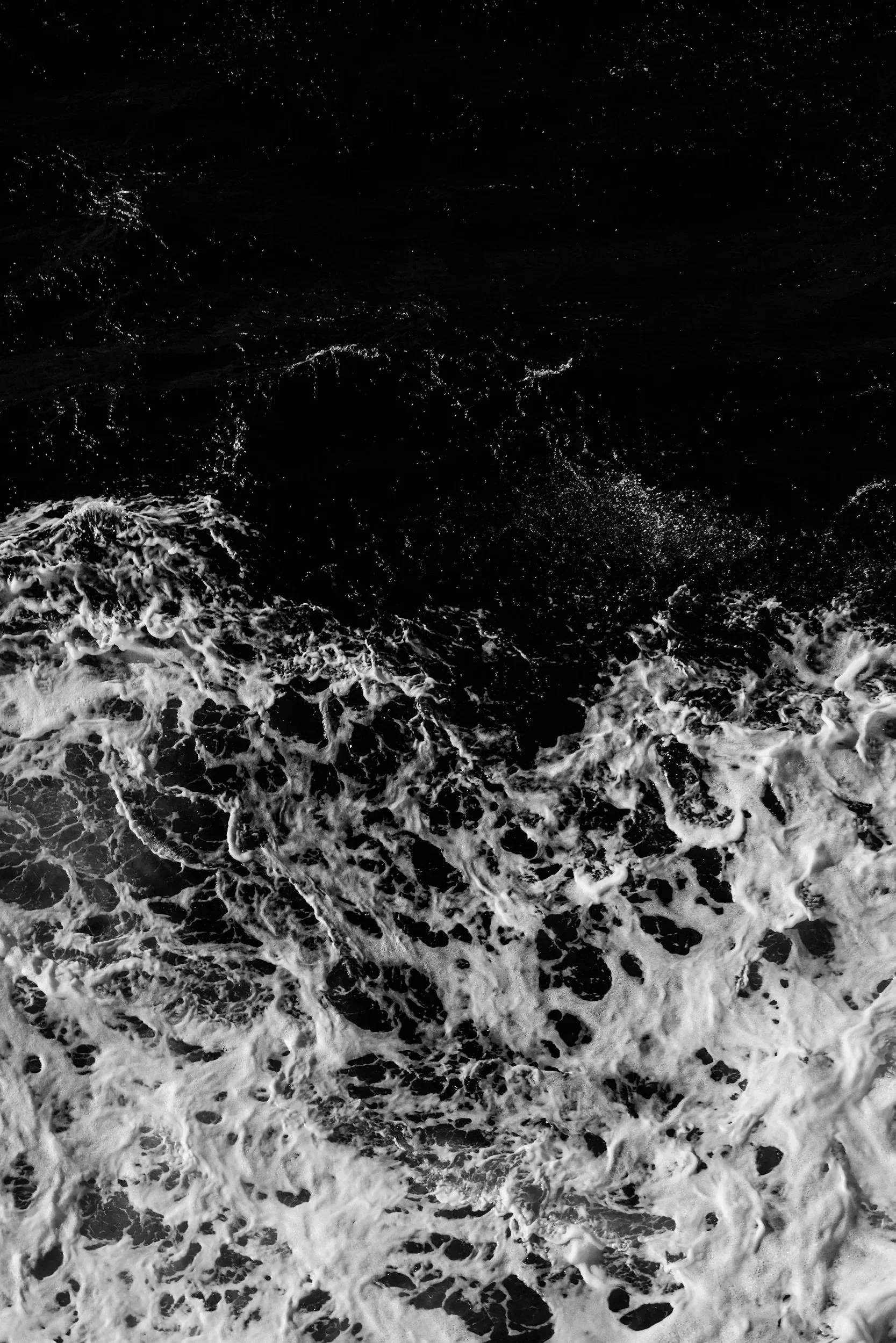 Black and white photograph of ocean water with ripples and foam.