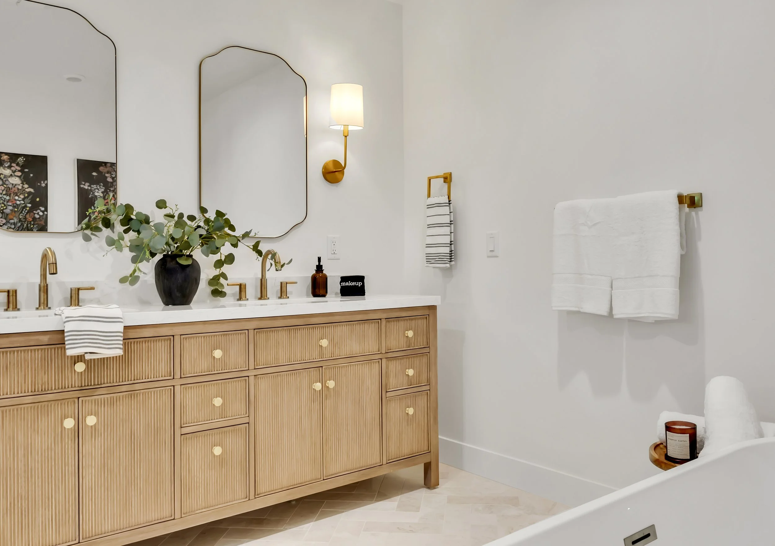 Elegant primary bathroom in Phoenix, AZ showcasing a double wood vanity with gold hardware, modern mirrors, and soft neutral tones.