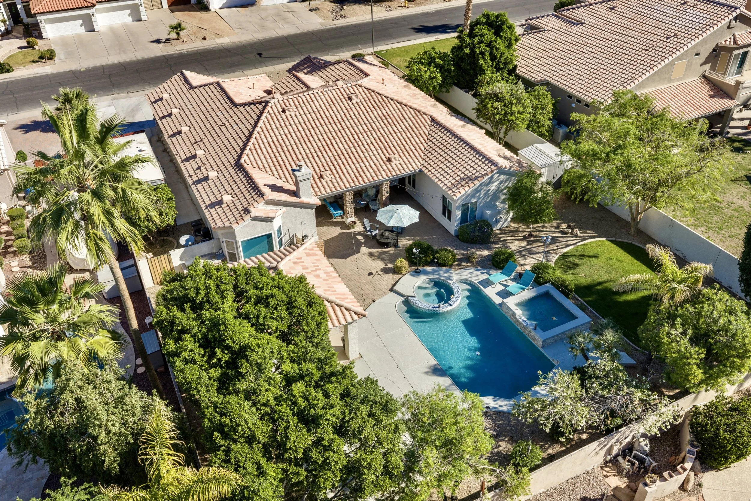 Aerial real estate photography showcases a beautiful Gilbert, AZ home with a spacious backyard, pool, and lush greenery, perfect for outdoor living and entertaining.