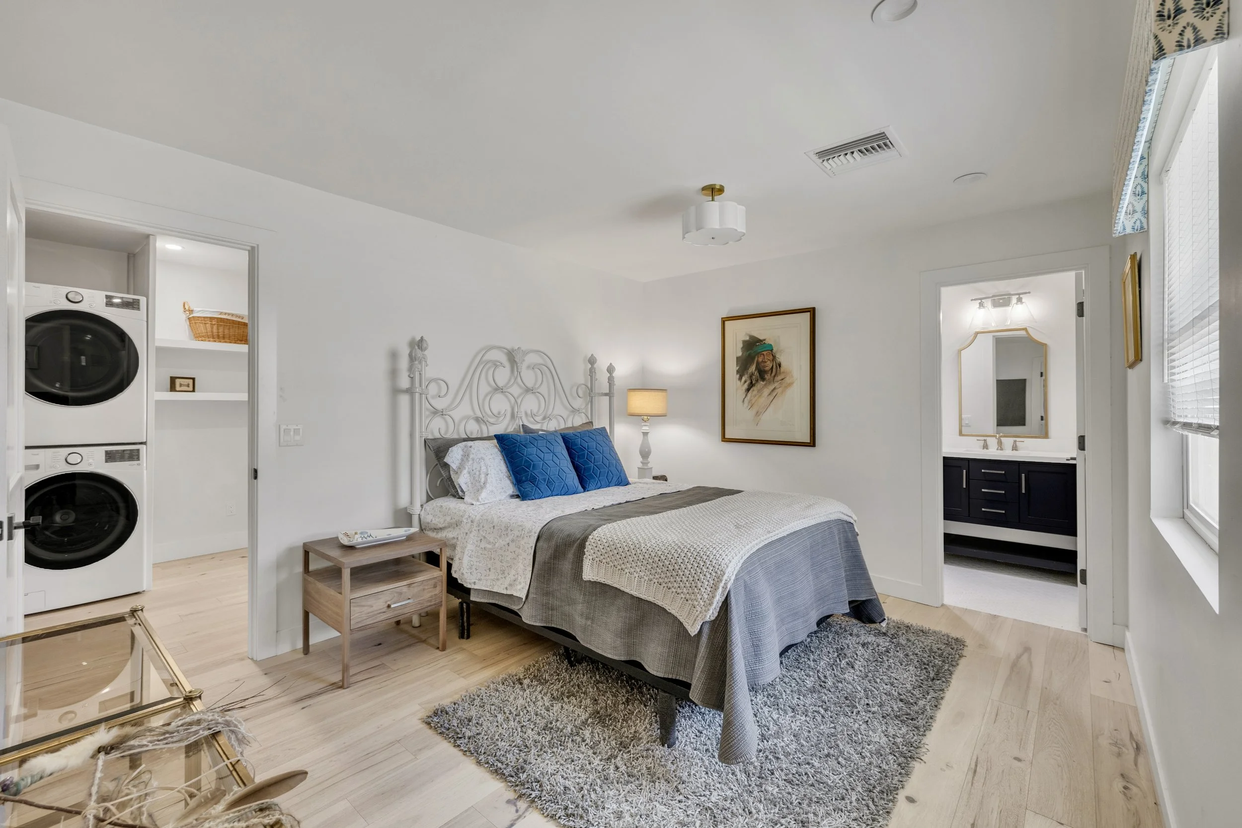 This bright bedroom with washer and dryer area showcases a clean design and cozy decor in Phoenix, AZ, captured through professional real estate photography.