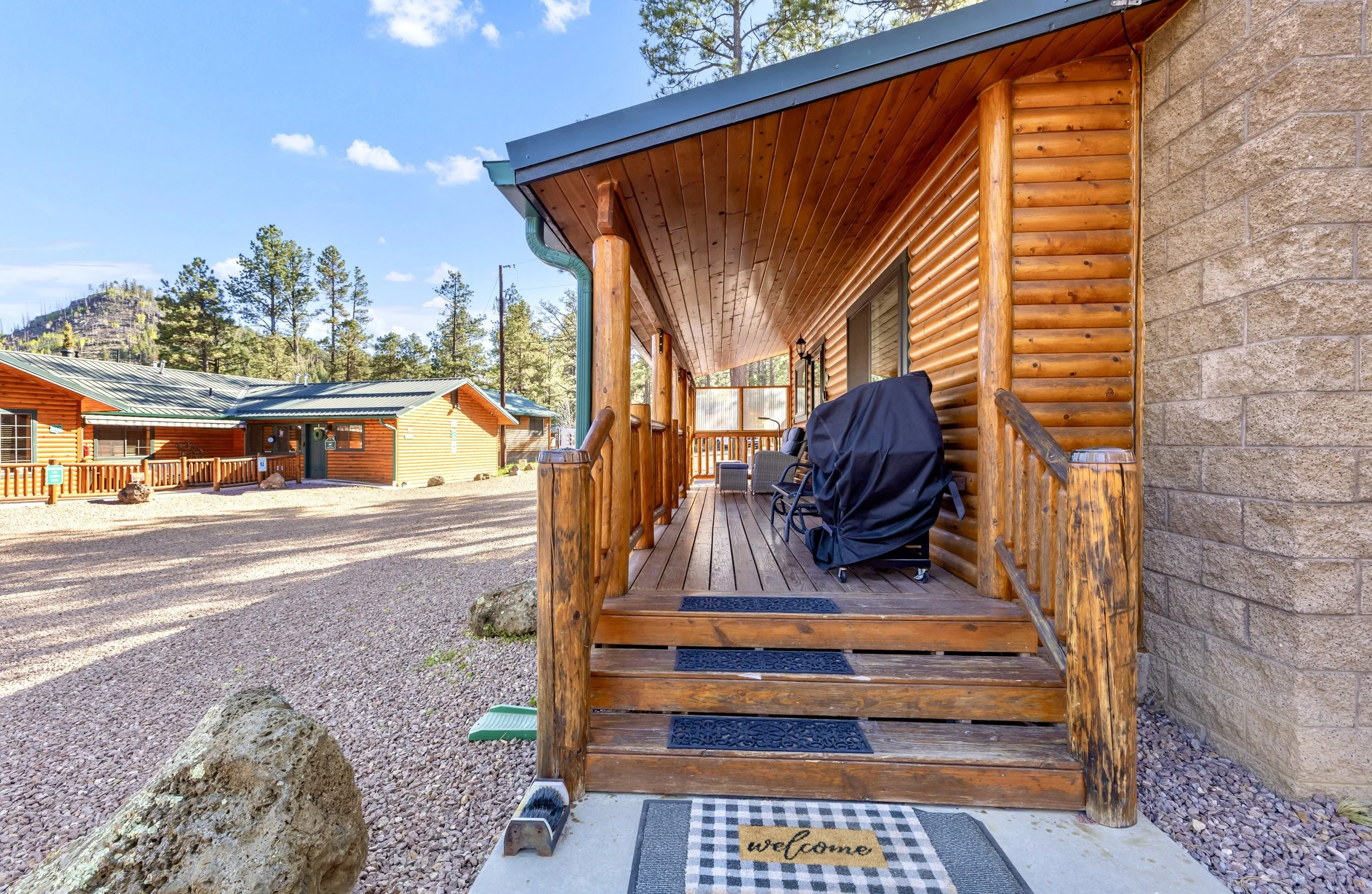 This cozy log cabin with a wooden front porch and mountain views showcases charming real estate photography in Greer, AZ.